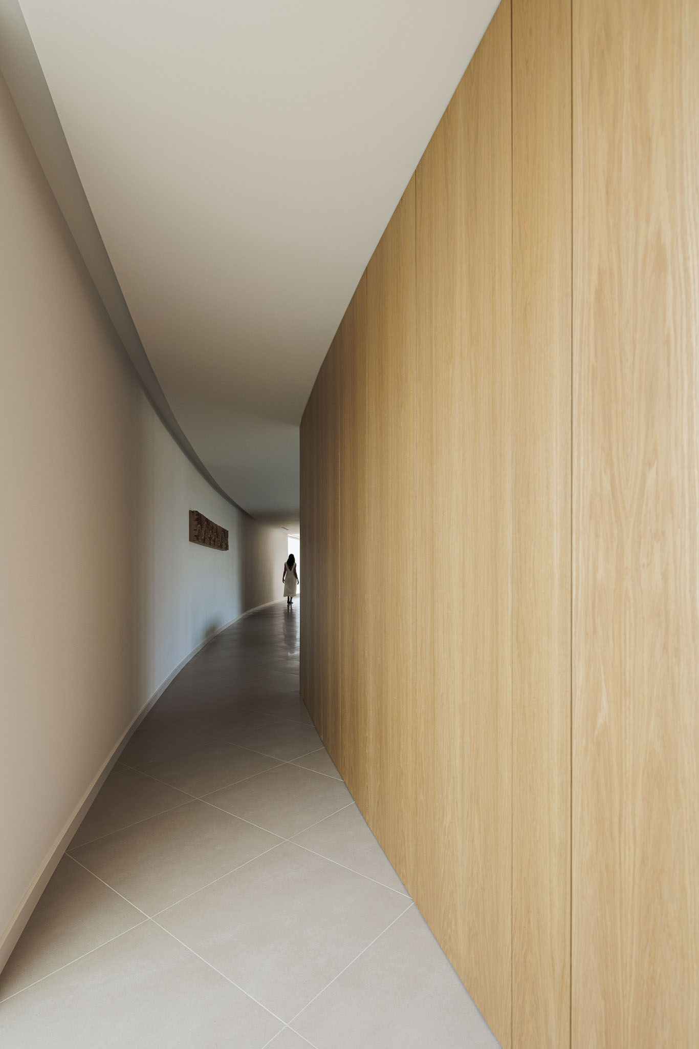 Corredor: Corredor curvo com pavimento cerâmico e armários embutidos de madeira clara. — Casa 109 arquitetura Frari em Vagos