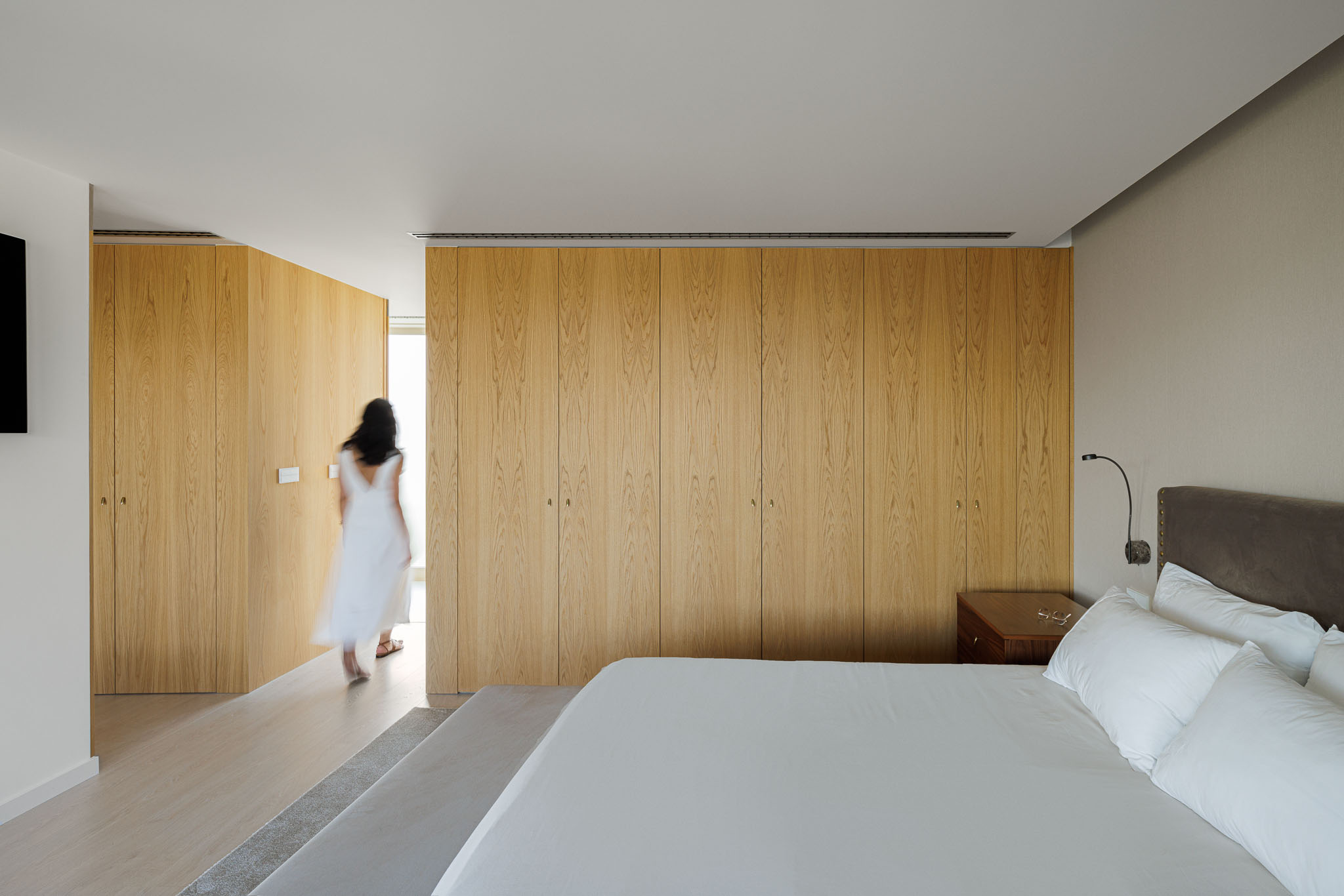 Quarto: Cama de casal com cabeceira almofadada, armários embutidos de madeira clara e alcatifa. — Casa 109 arquitetura Frari em Vagos
