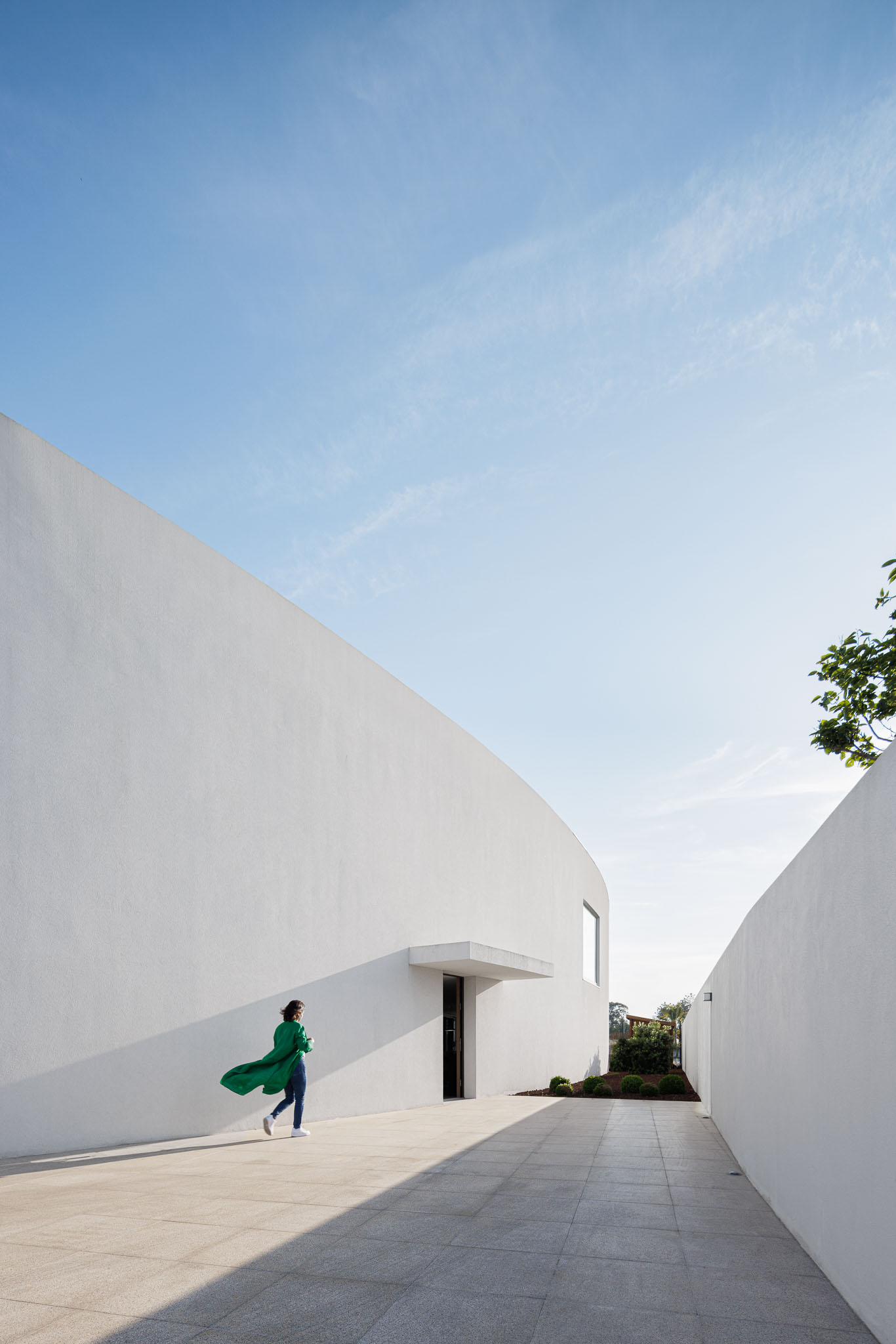 Exterior: Entrada da casa com paredes brancas altas e pavimento em pedra. — Casa 109 arquitetura Frari em Vagos
