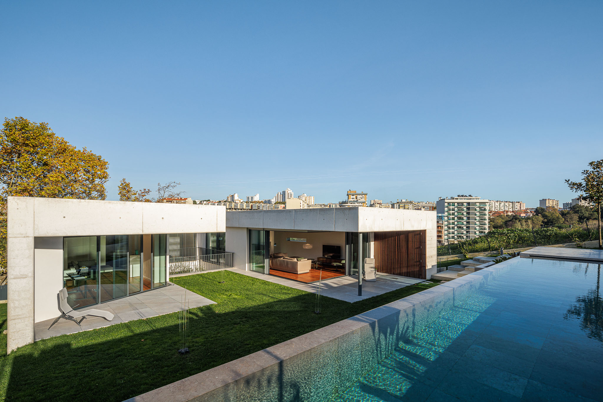Exterior: Vista da moradia com piscina, jardim e zona de estar exterior. Arquitetura moderna em betão. — CONCRETE 11 arquitetura Cage Atelier em Lisboa
