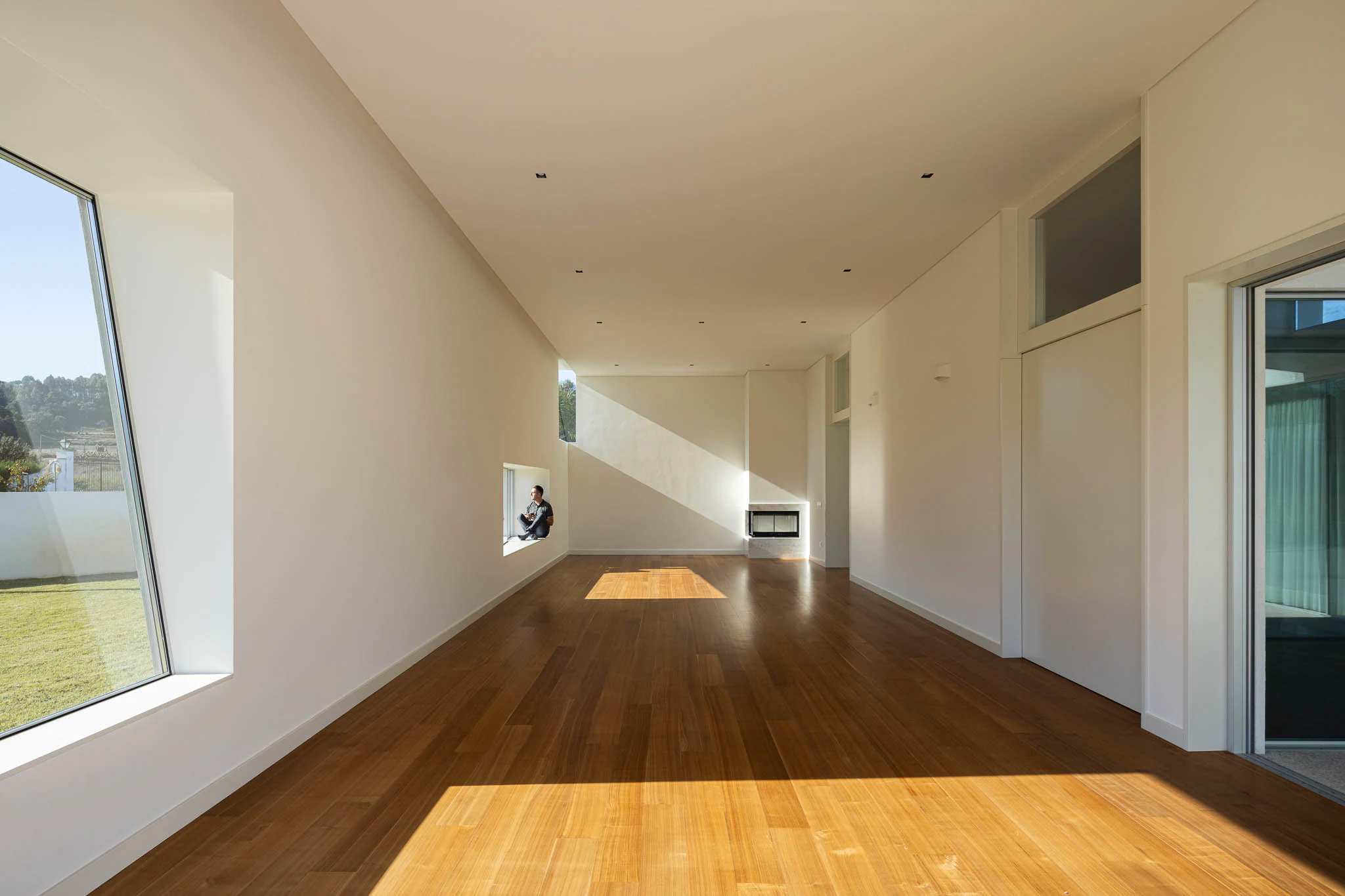 Detalhe de janela inclinada com caixilharia metálica, fachada branca e céu azul. — Casa em Brufe arquitetura Oval em Vila Nova de Famalicão