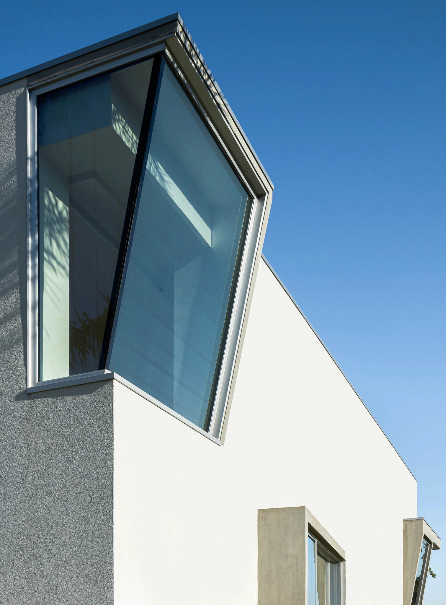 Exterior da casa com janelas geométricas, fachada branca e jardim com palmeiras. — Casa em Brufe arquitetura Oval em Vila Nova de Famalicão