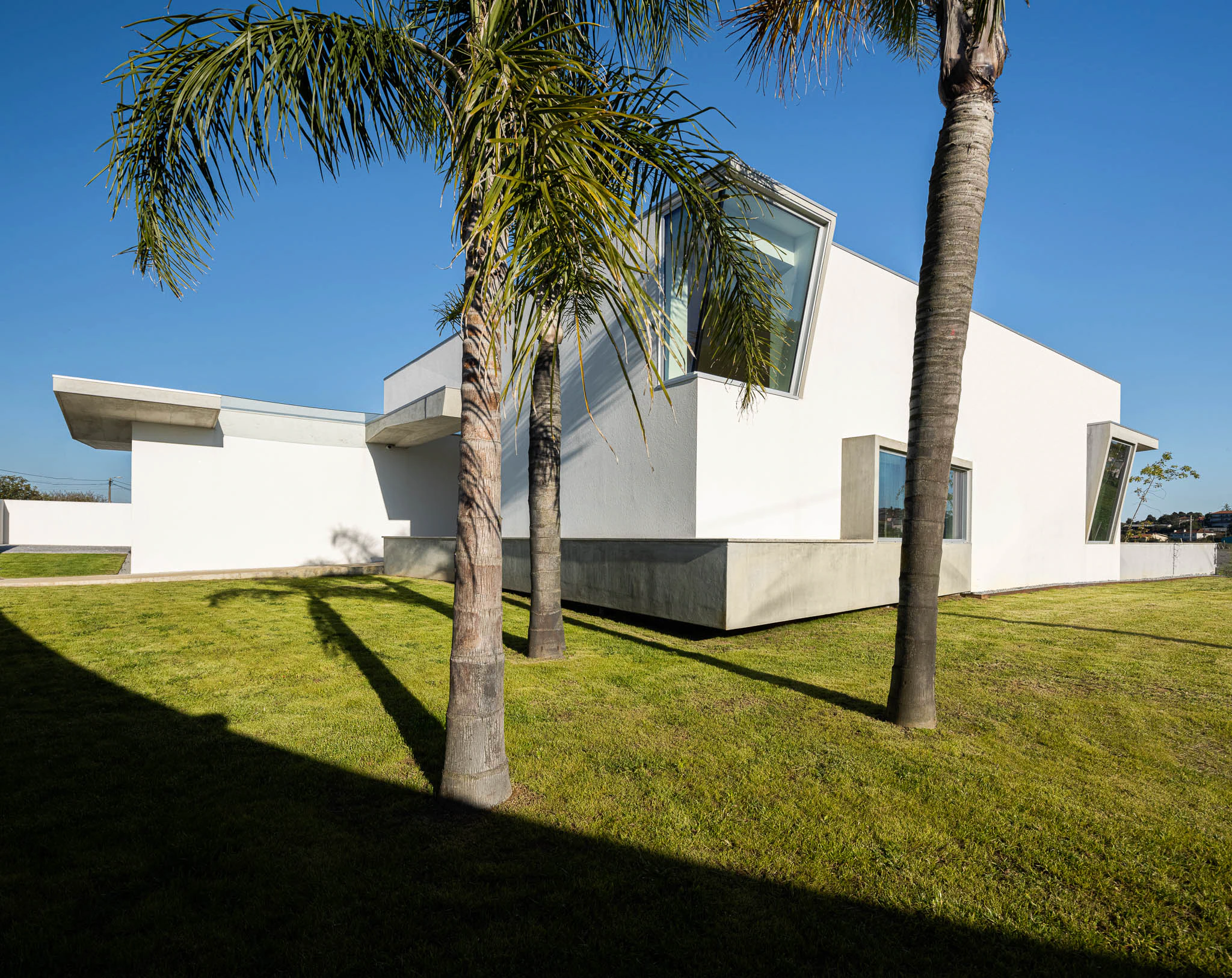 Vista lateral da casa com cobertura de betão, ripas de madeira e parede branca. — Casa em Brufe arquitetura Oval em Vila Nova de Famalicão
