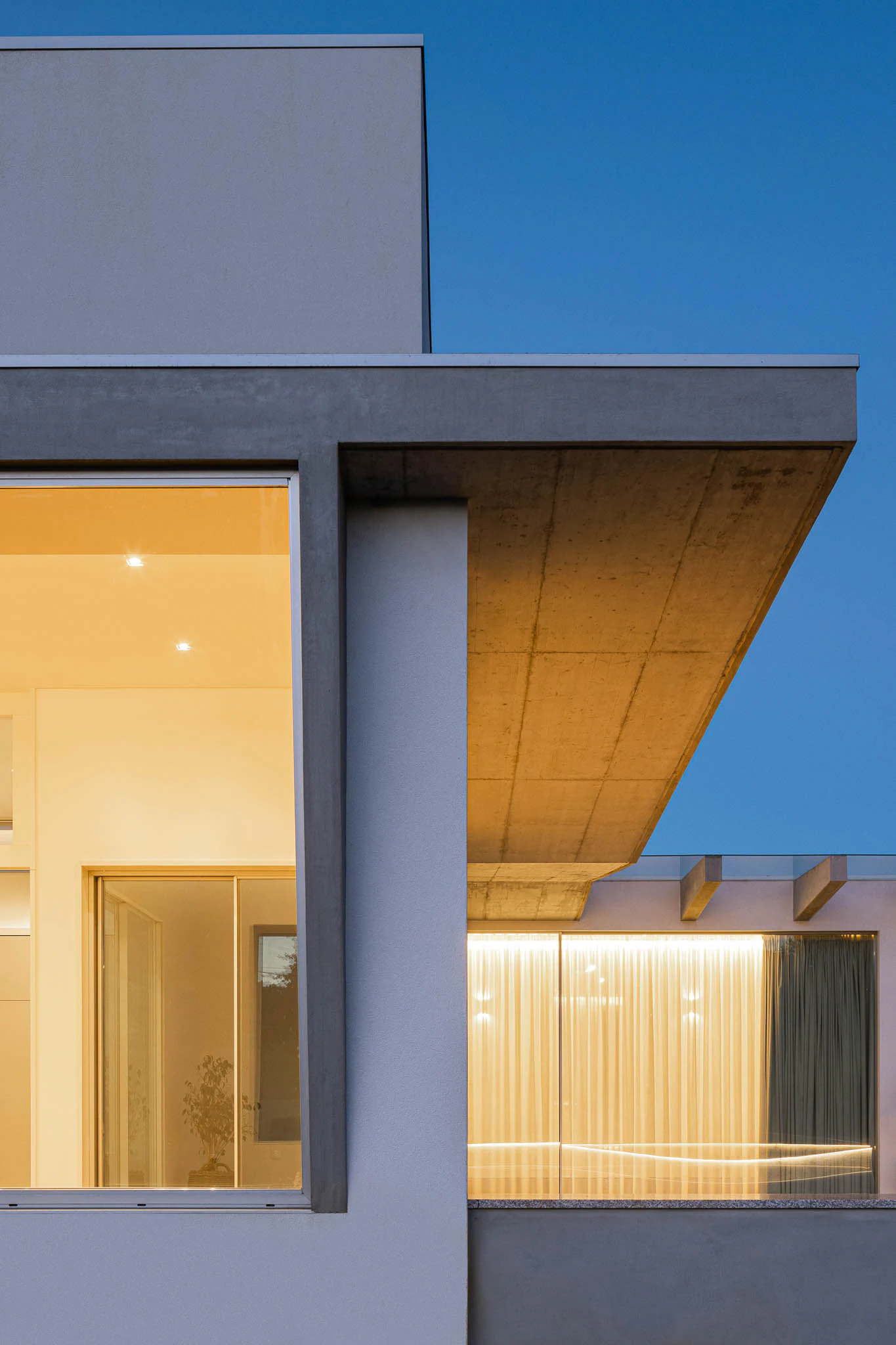 Fachada com janelas amplas, cobertura de betão e iluminação noturna, sob céu estrelado. — Casa em Brufe arquitetura Oval em Vila Nova de Famalicão