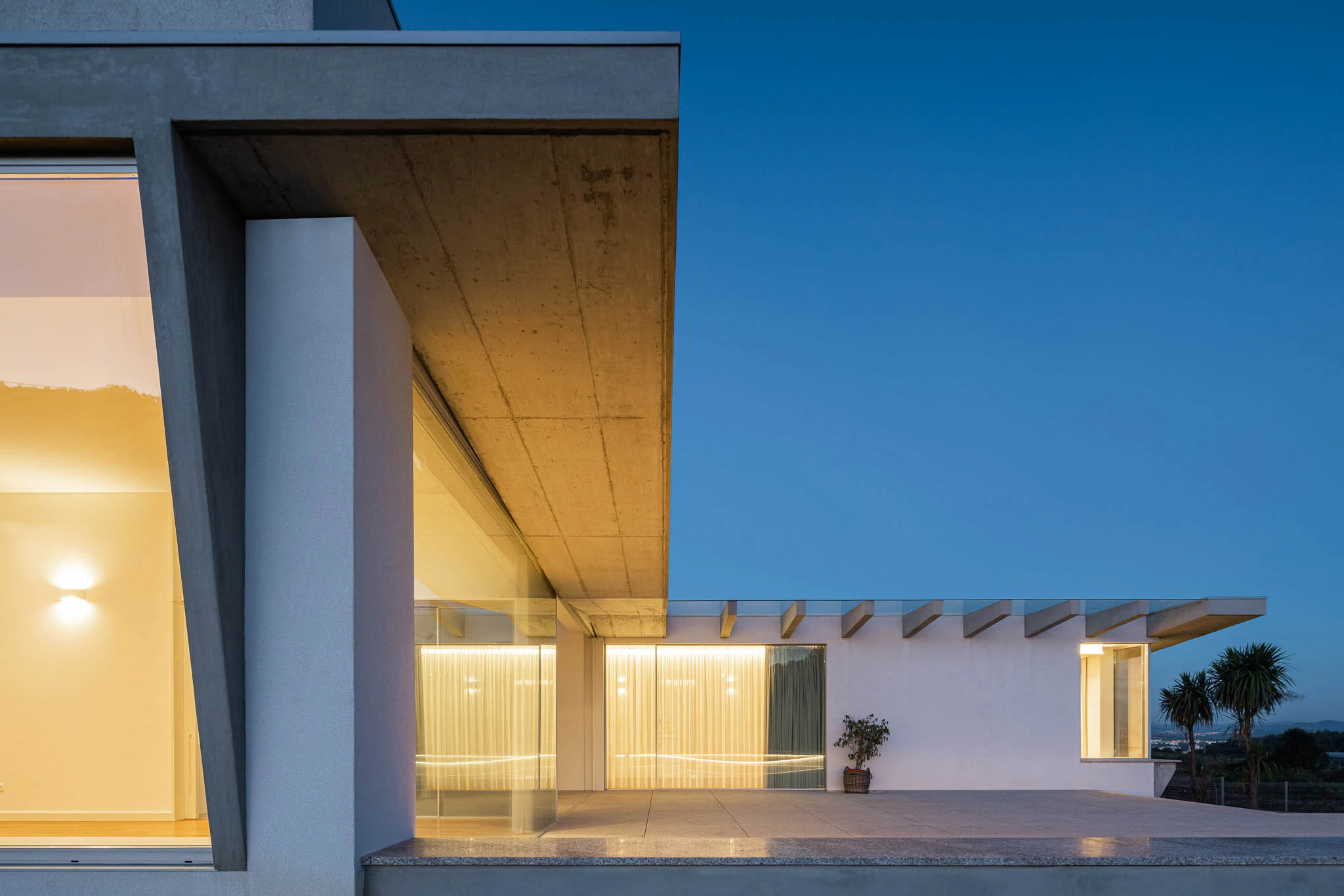 Vista geral da casa com iluminação noturna, jardim e arquitetura moderna. — Casa em Brufe arquitetura Oval em Vila Nova de Famalicão