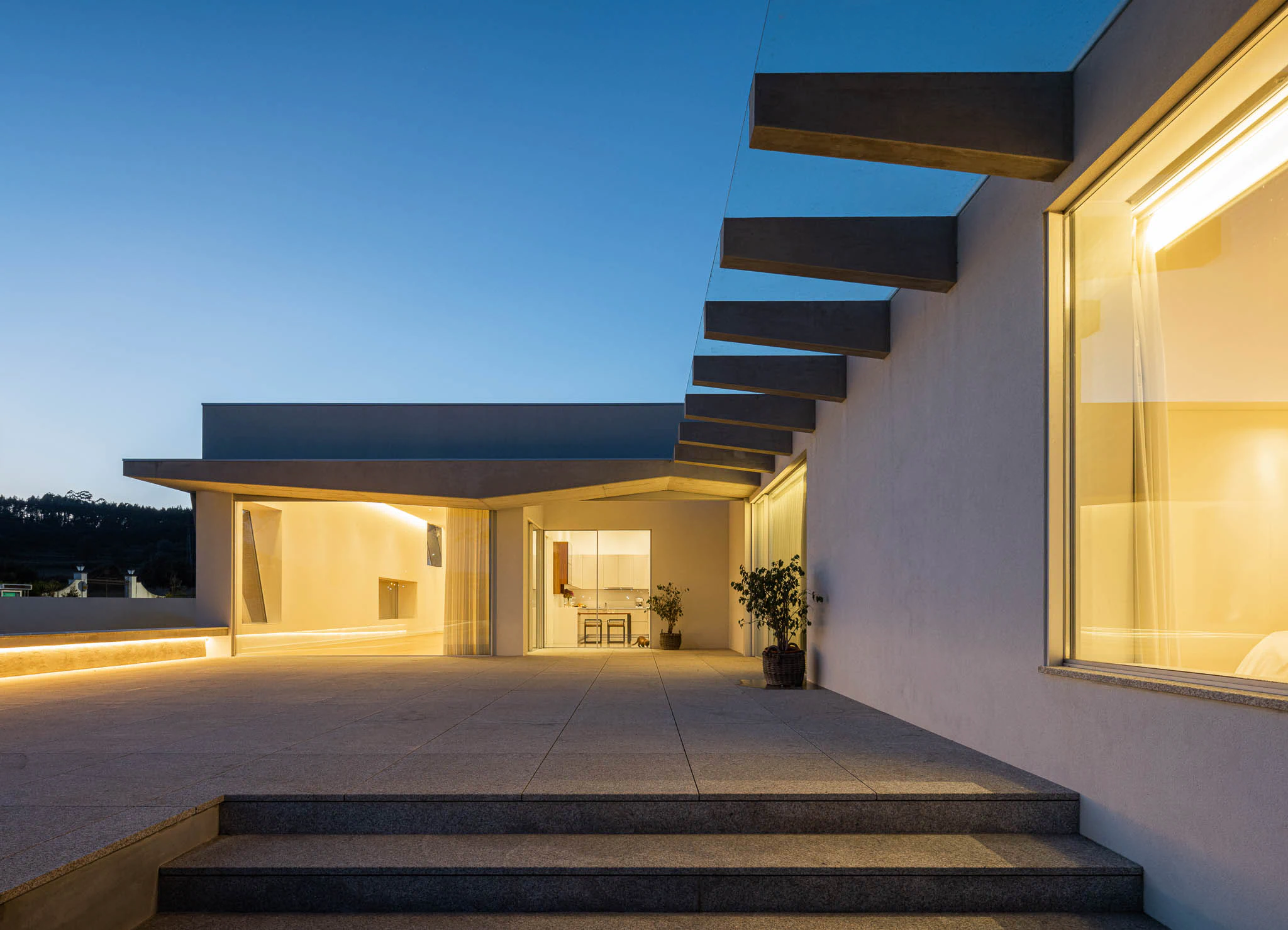 Terraço com iluminação embutida, vista para a paisagem rural e arquitetura moderna. — Casa em Brufe arquitetura Oval em Vila Nova de Famalicão