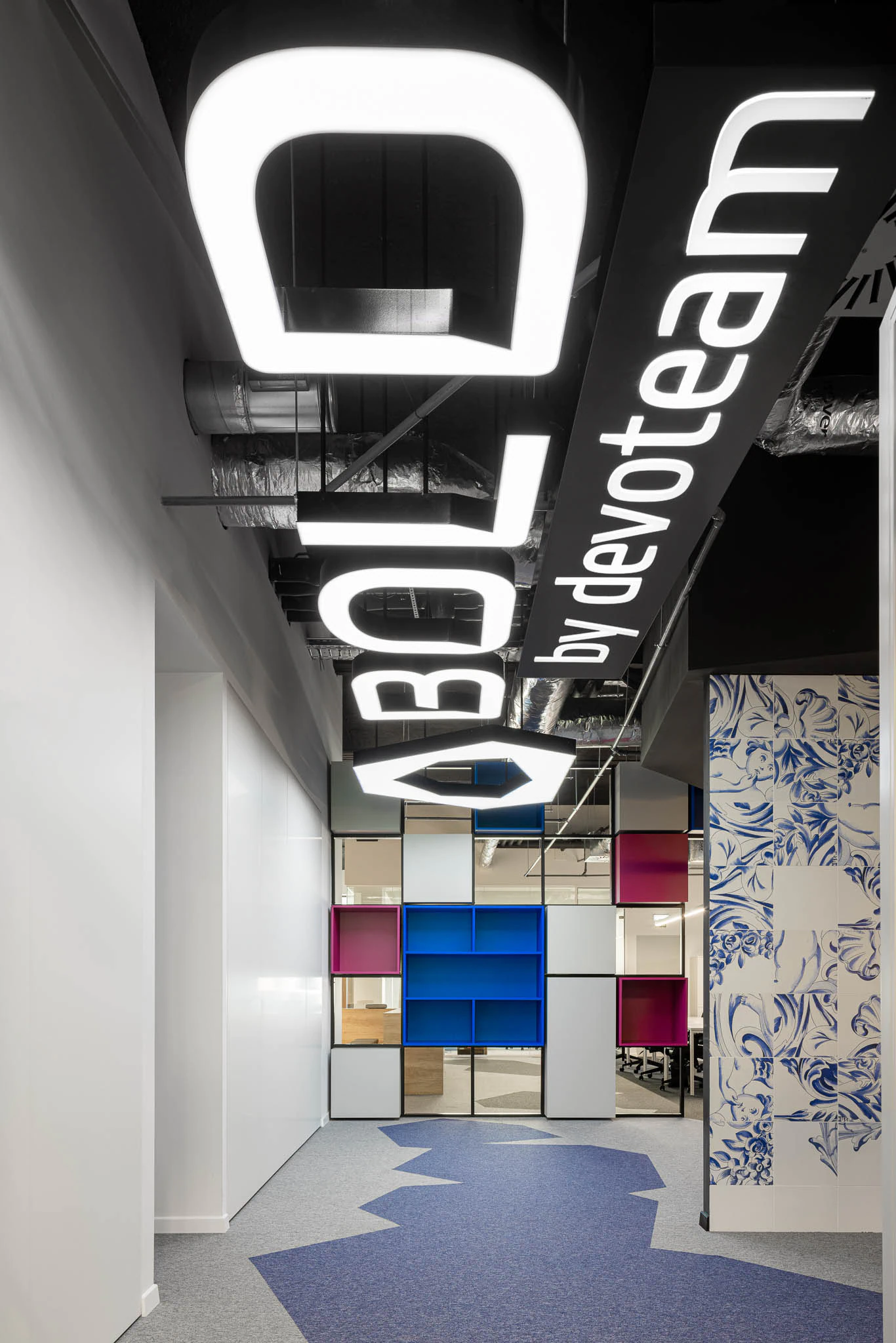 Corredor com iluminação suspensa "BOLD", estantes coloridas e padrão de azulejos azuis. — Bold by Devoteam: Escritório Porto arquitetura Inception Architects Studio em Porto