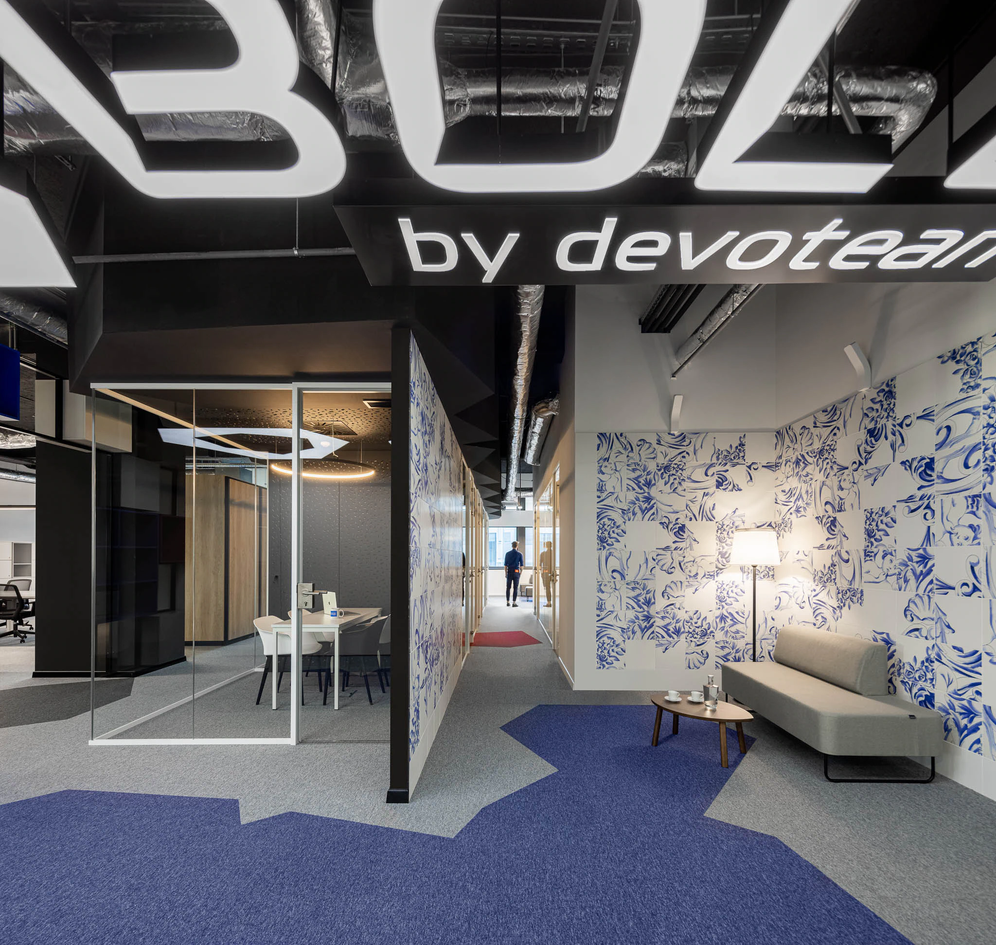 Espaço de escritório com sala de reunião envidraçada, zona de estar com sofá e parede com padrão floral azul. — Bold by Devoteam: Escritório Porto arquitetura Inception Architects Studio em Porto