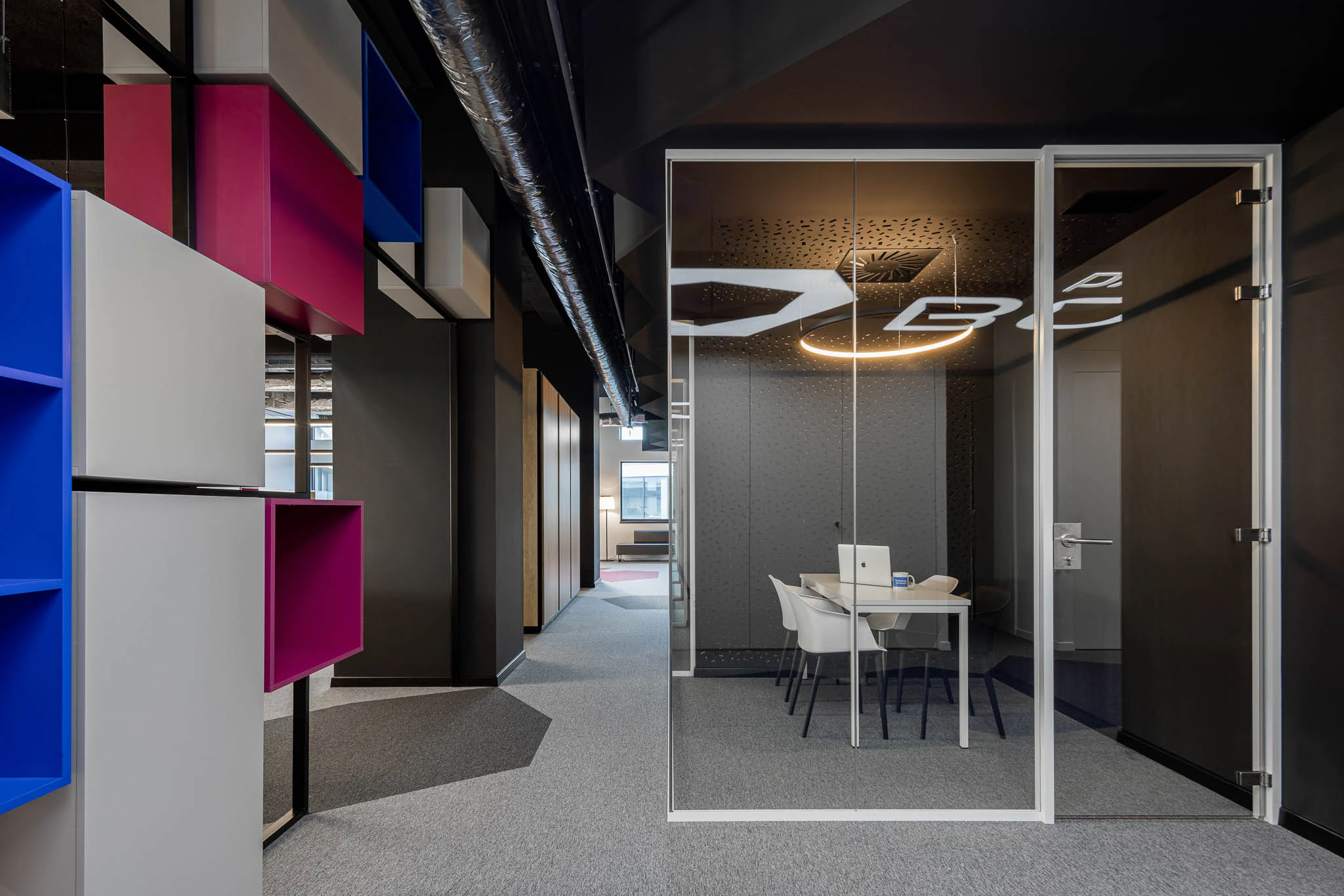 Corredor com estantes coloridas, sala de reunião envidraçada e iluminação circular suspensa. — Bold by Devoteam: Escritório Porto arquitetura Inception Architects Studio em Porto