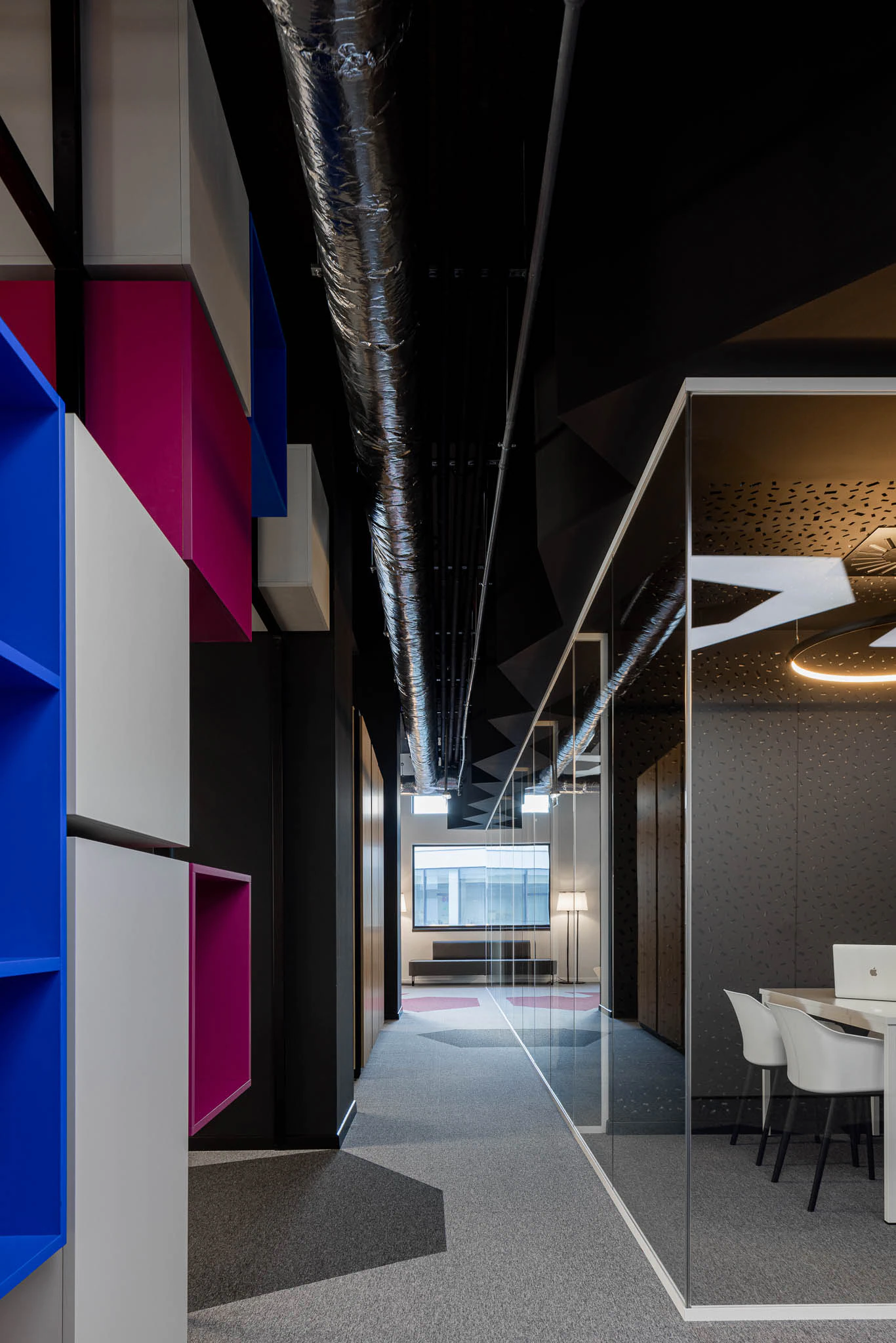 Visão do corredor com estantes coloridas, tubagens expostas e sala de reunião envidraçada ao fundo. — Bold by Devoteam: Escritório Porto arquitetura Inception Architects Studio em Porto