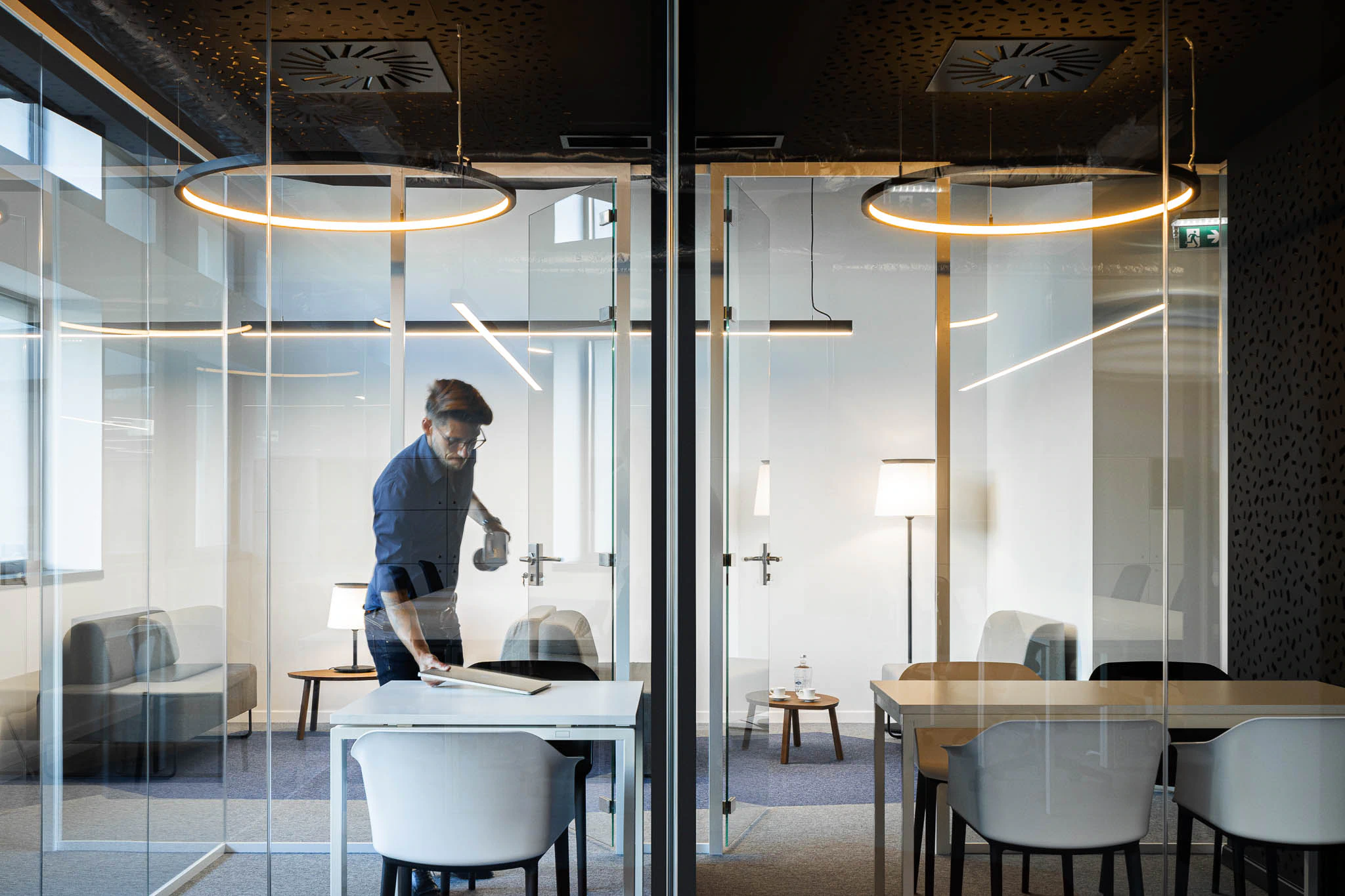 Salas de reunião envidraçadas com iluminação circular suspensa e mobiliário moderno. — Bold by Devoteam: Escritório Porto arquitetura Inception Architects Studio em Porto