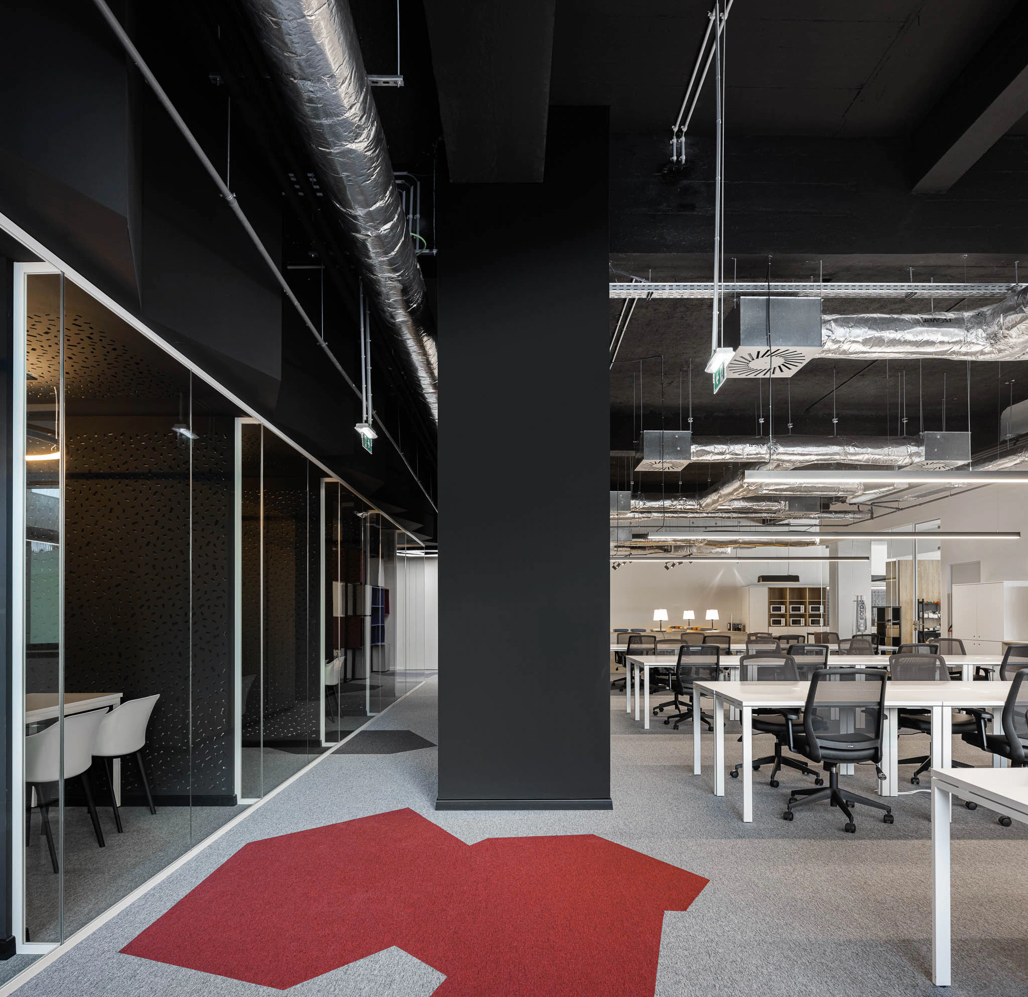 Corredor com salas de reunião envidraçadas, espaço de trabalho aberto e tapete com seta vermelha. — Bold by Devoteam: Escritório Porto arquitetura Inception Architects Studio em Porto