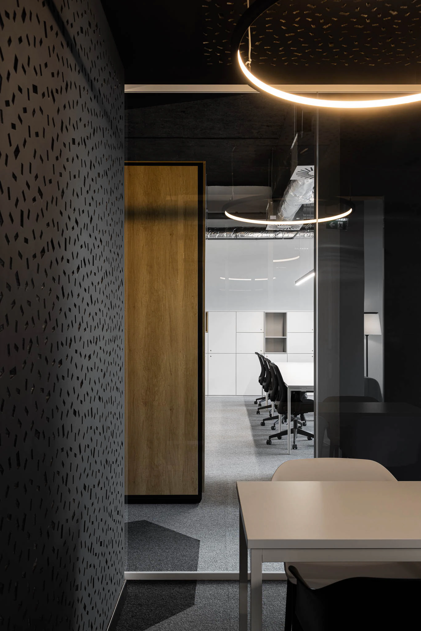 Detalhe de divisória com padrão, porta de madeira e sala de reunião envidraçada com iluminação circular. — Bold by Devoteam: Escritório Porto arquitetura Inception Architects Studio em Porto
