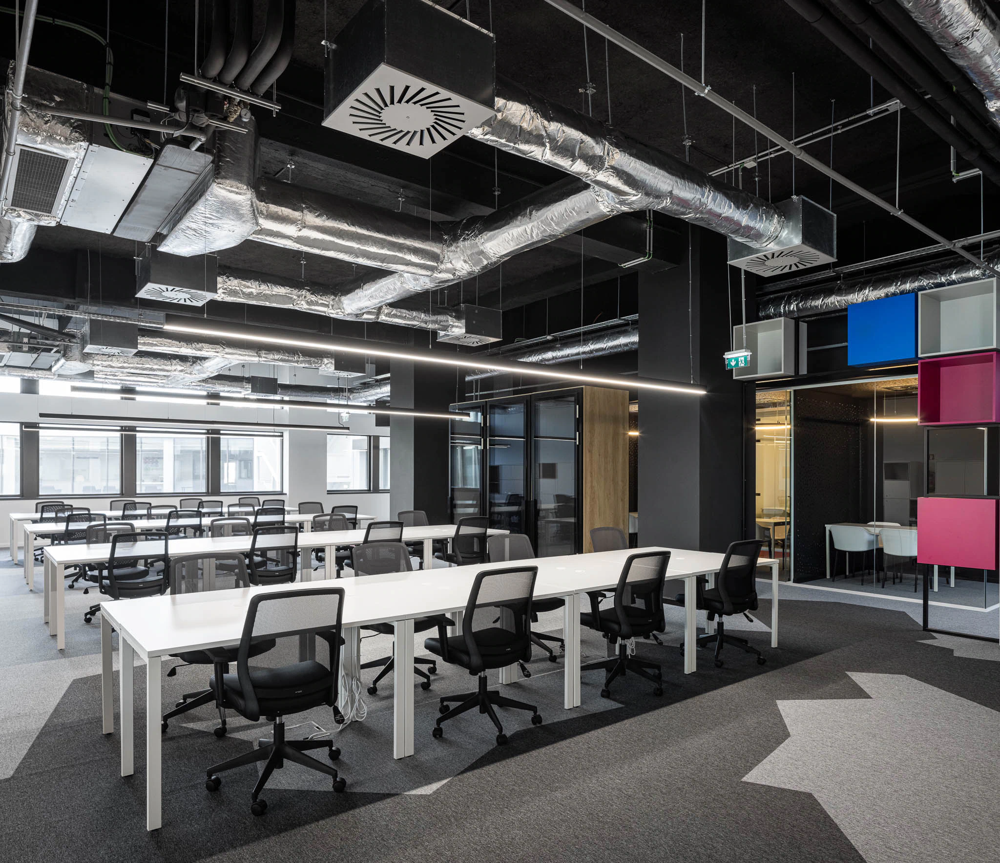 Espaço de trabalho amplo com secretárias brancas, cadeiras pretas e iluminação industrial exposta. — Bold by Devoteam: Escritório Porto arquitetura Inception Architects Studio em Porto