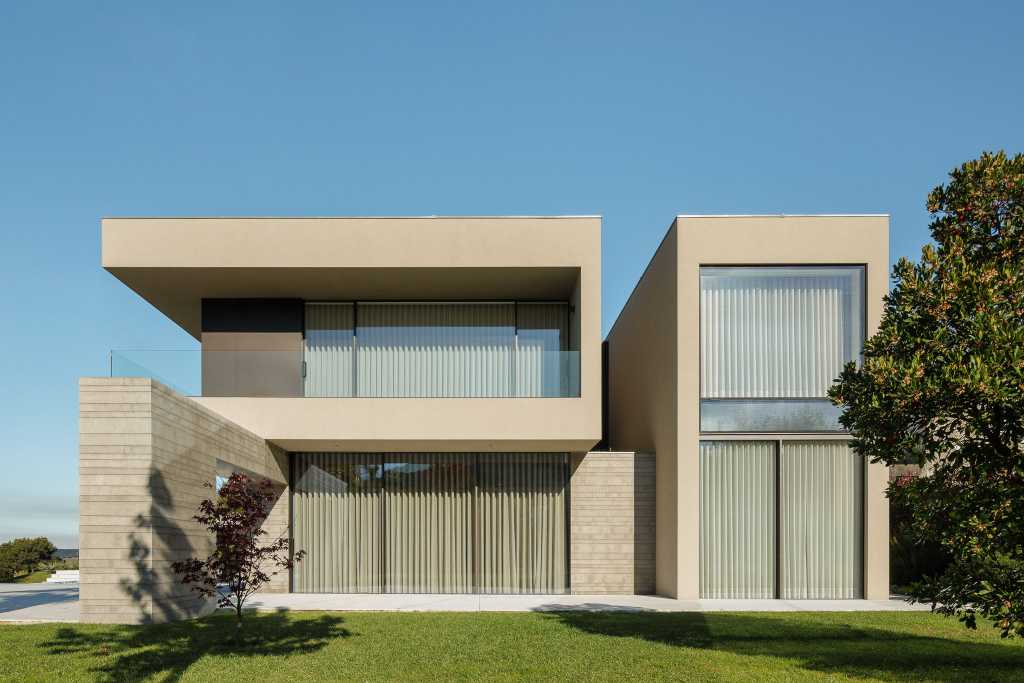 Fachada: Vista exterior da casa com dois volumes distintos e revestimento em tons neutros. — Casa D arquitetura L2C Arquitetura em Braga