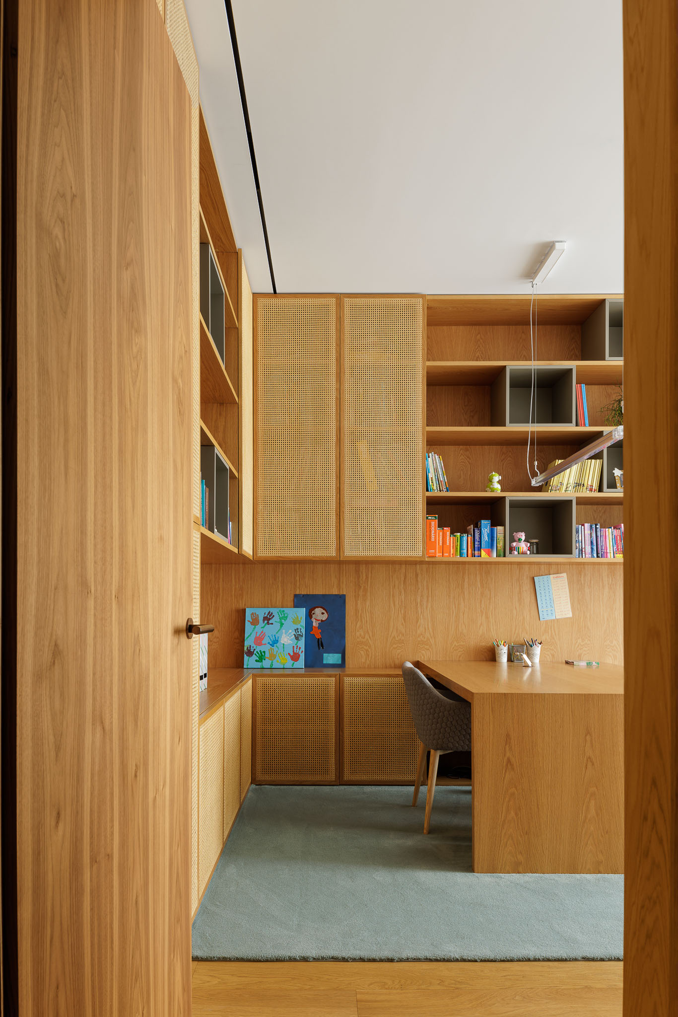 Escritório: Escritório com secretária em madeira, estantes com prateleiras e alcatifa azul. — Casa D arquitetura L2C Arquitetura em Braga
