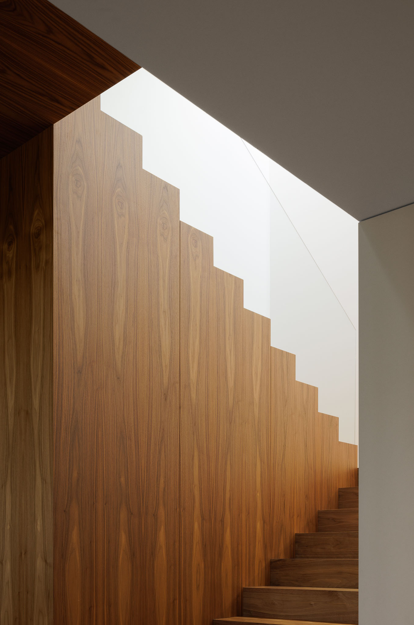 Escadas: Detalhe da parede revestida a madeira das escadas com iluminação natural zenital. — Casa D arquitetura L2C Arquitetura em Braga