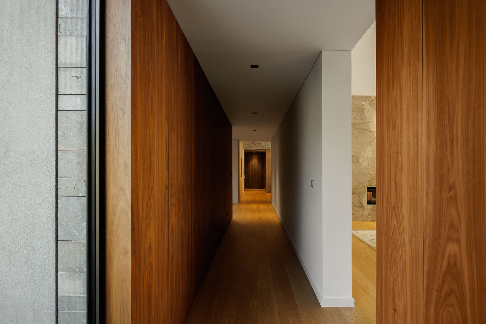 Corredor: Corredor com pavimento em madeira, paredes revestidas a madeira e porta para sala de estar. — Casa D arquitetura L2C Arquitetura em Braga