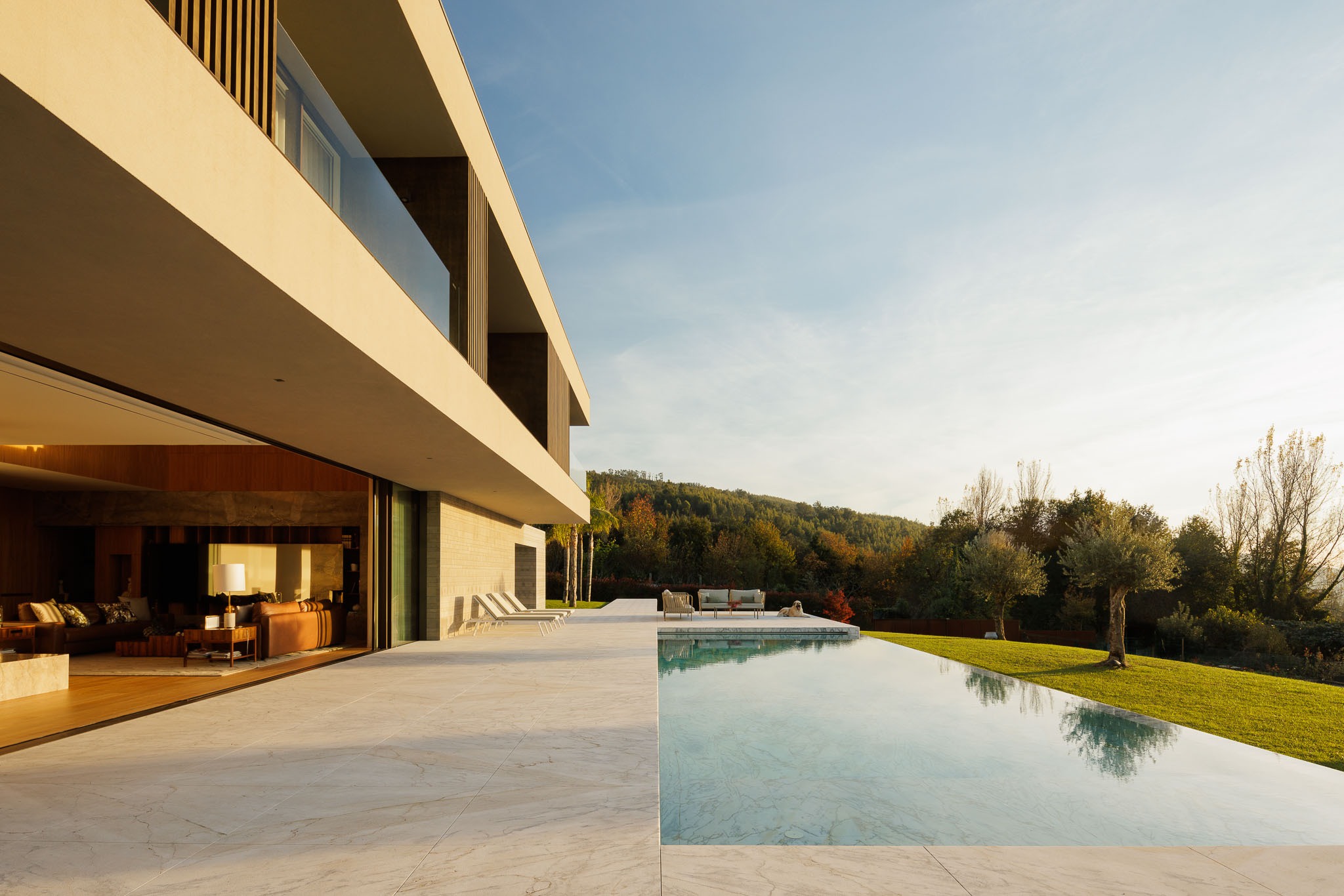 Sala de estar: Sala de estar com sofás em pele, lareira em mármore e vista para o exterior. — Casa D arquitetura L2C Arquitetura em Braga