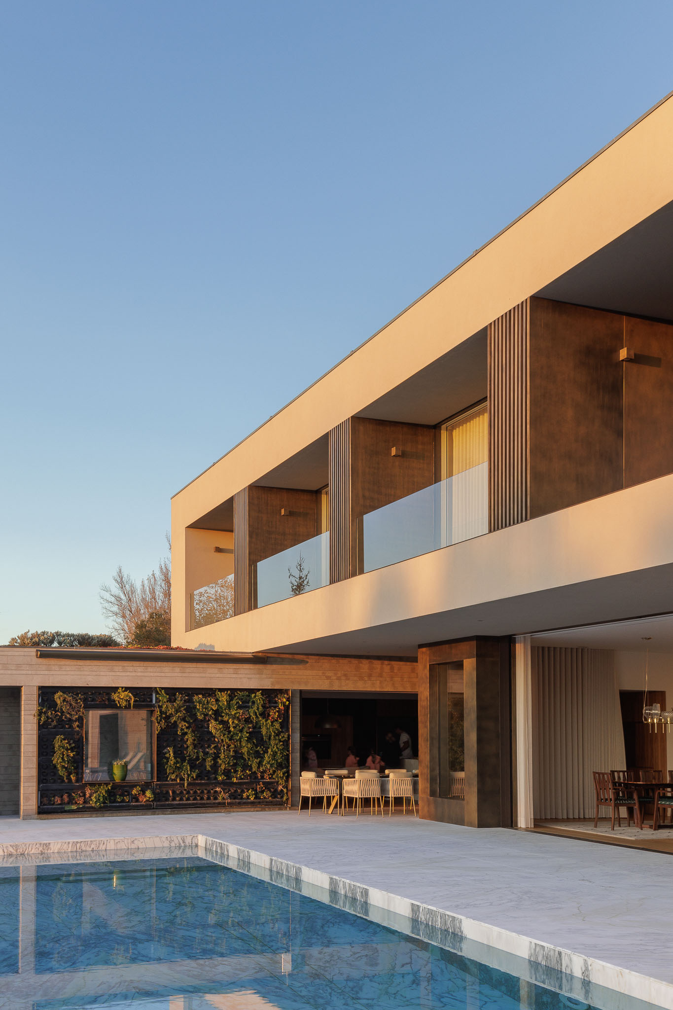 Cozinha: Cozinha com mesa redonda, armários em madeira e vista para o alpendre com plantas. — Casa D arquitetura L2C Arquitetura em Braga