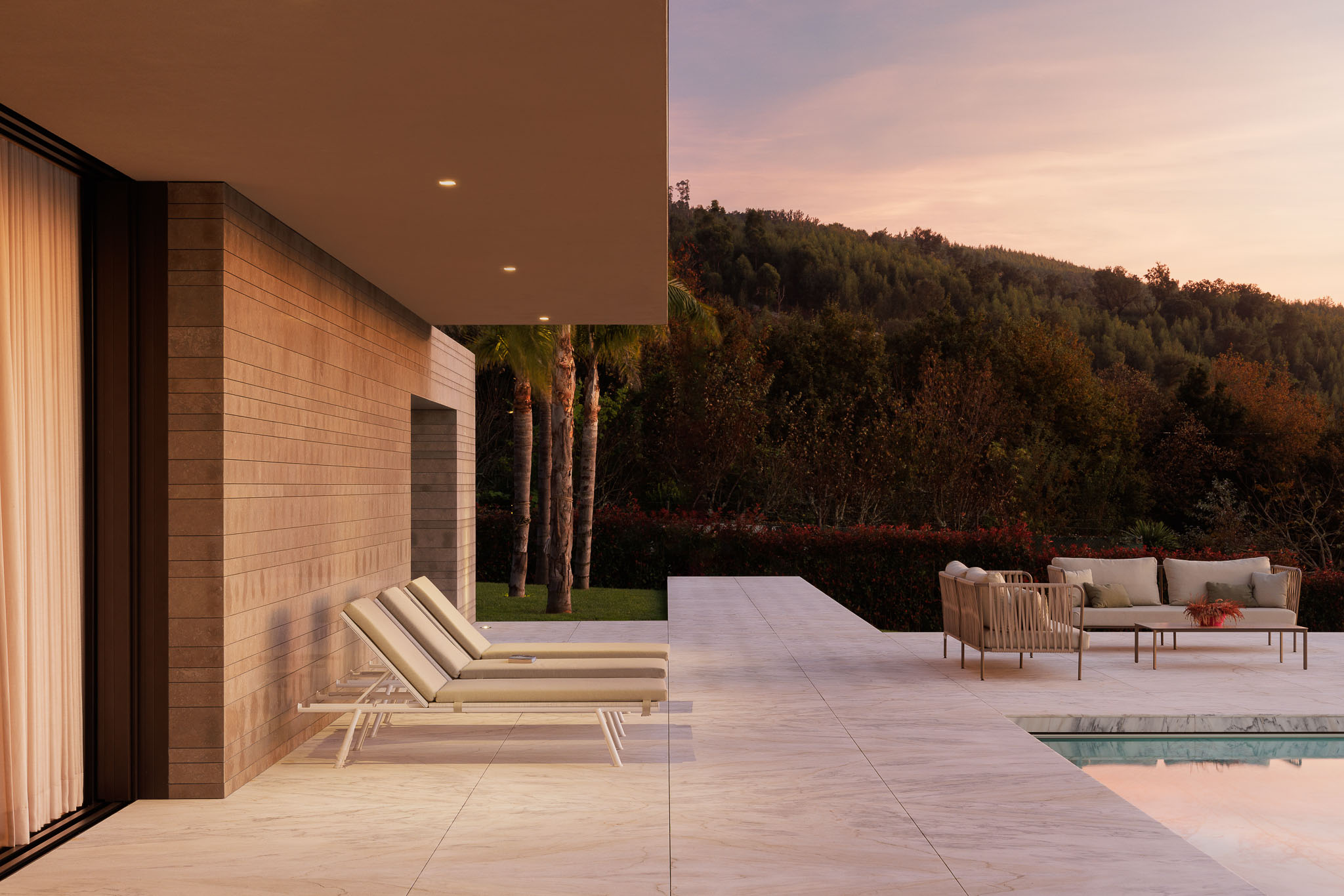 Exterior: Vista da casa com piscina, alpendre com plantas e zona de jantar exterior ao entardecer. — Casa D arquitetura L2C Arquitetura em Braga
