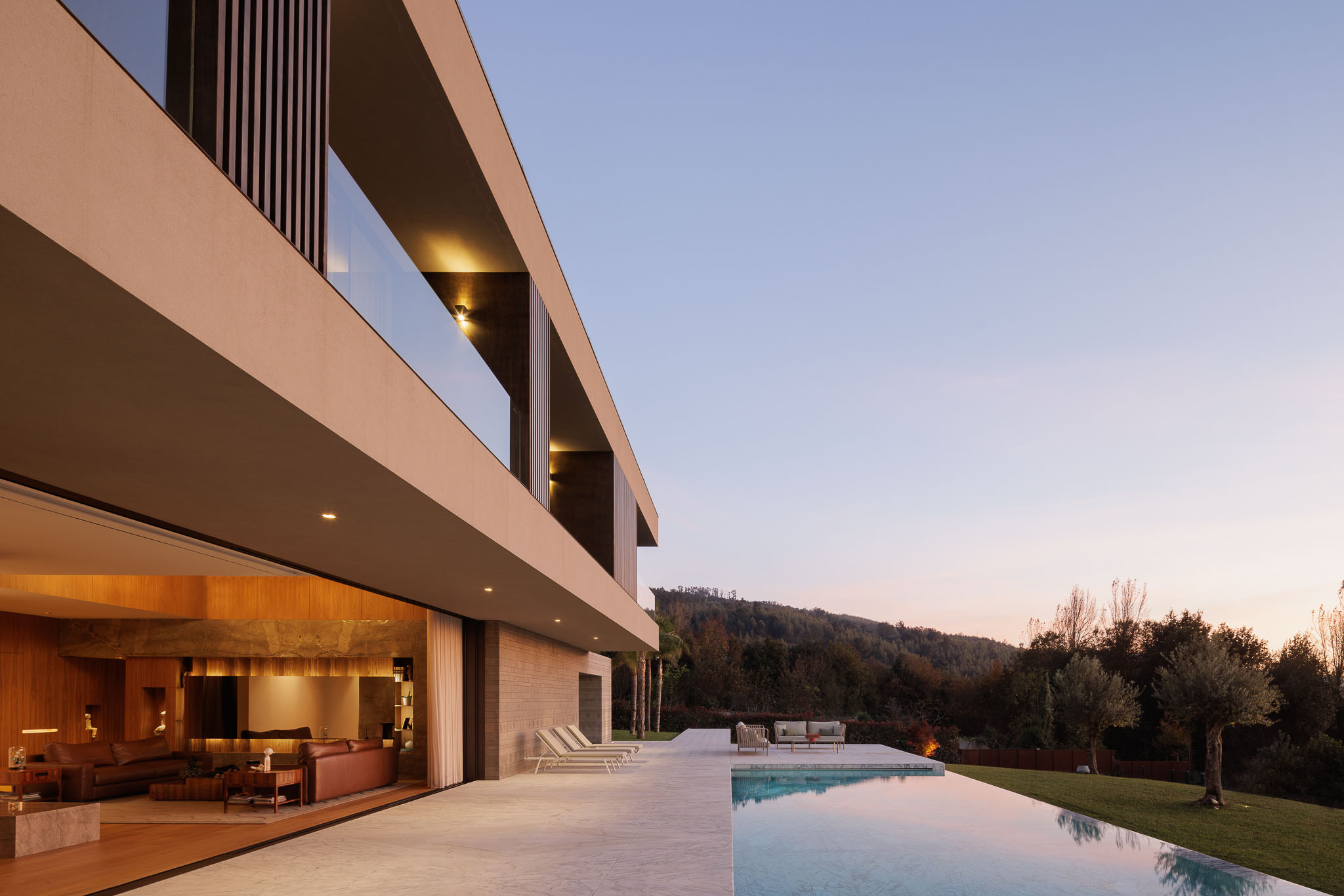 Exterior: Vista da casa com alpendre, piscina e céu ao entardecer. — Casa D arquitetura L2C Arquitetura em Braga