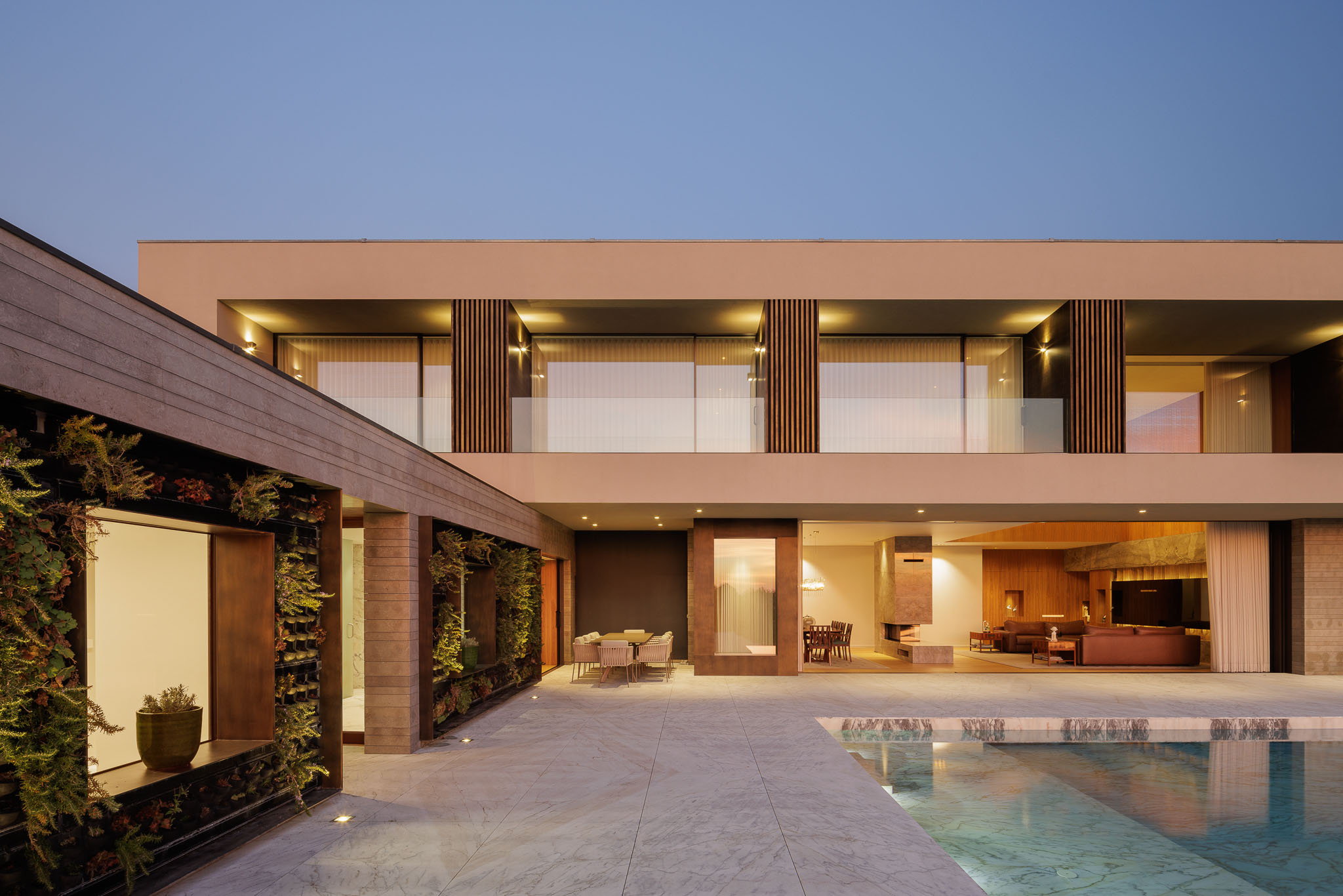 Sala de jantar: Sala de jantar com lareira em mármore, mesa de jantar e vista para o alpendre. — Casa D arquitetura L2C Arquitetura em Braga