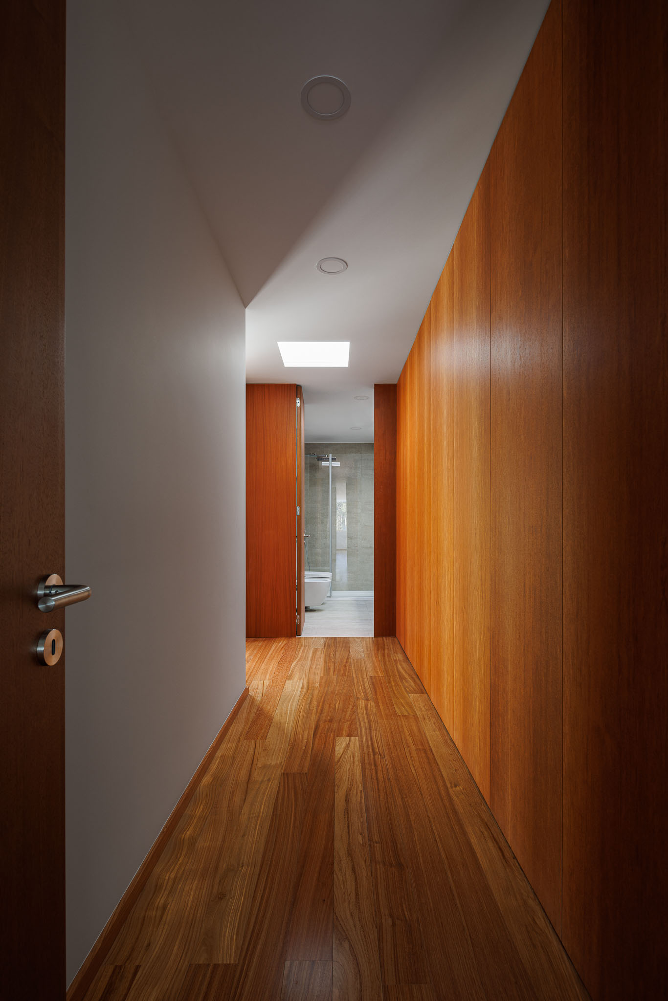 Corredor: Pavimento em madeira, paredes revestidas a madeira e luz zenital. — Casa R.V. arquitetura Atelier d´Arquitectura Lopes da Costa em Ovar