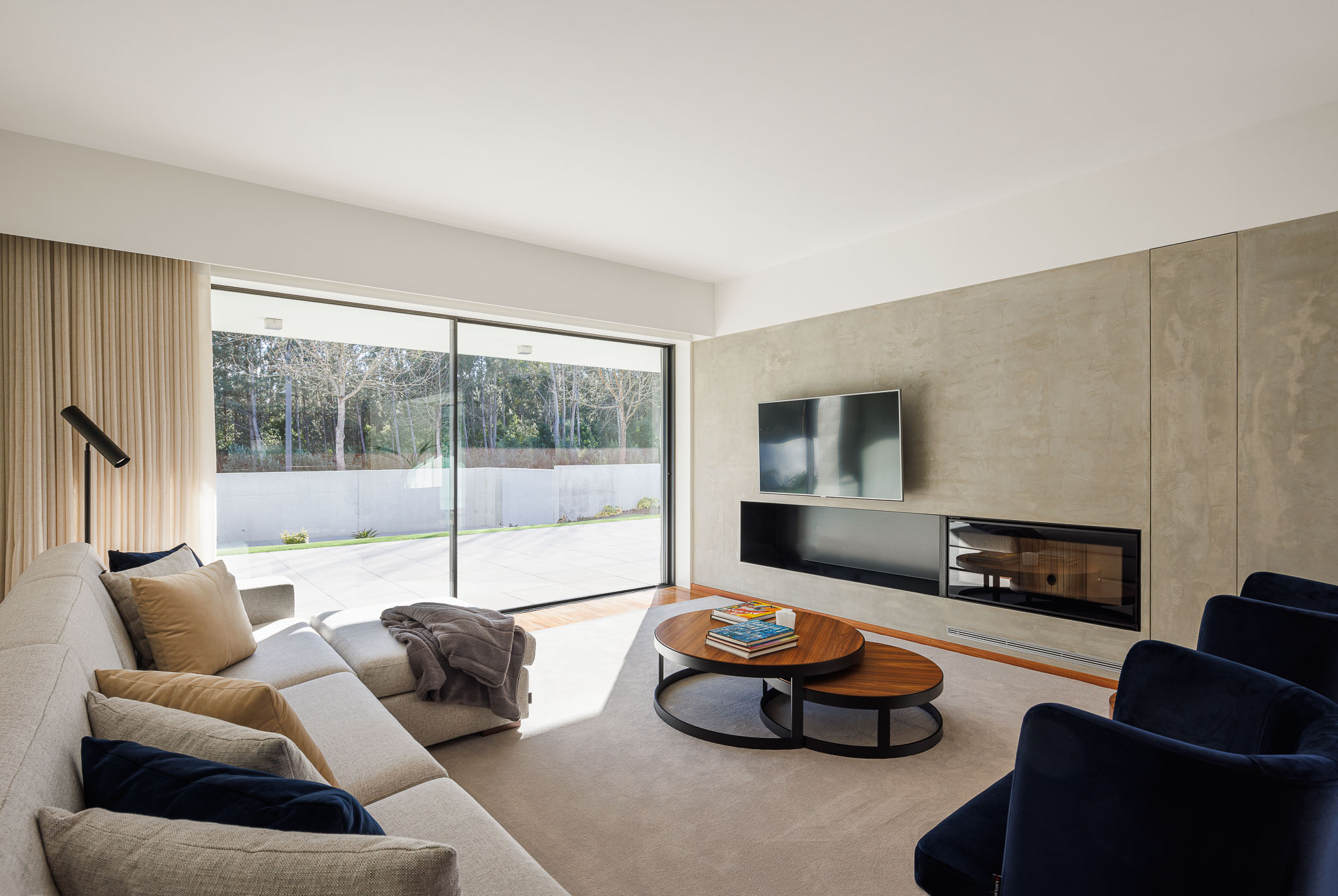 Sala de estar: Sofá cinzento, alcatifa clara, parede em betão e lareira moderna. — Casa R.V. arquitetura Atelier d´Arquitectura Lopes da Costa em Ovar