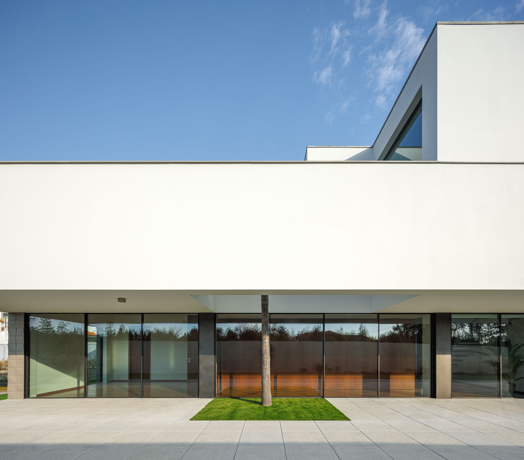 Fachada: Arquitetura moderna com linhas retas, revestimento branco e detalhes em pedra. — Casa R.V. arquitetura Atelier d´Arquitectura Lopes da Costa em Ovar
