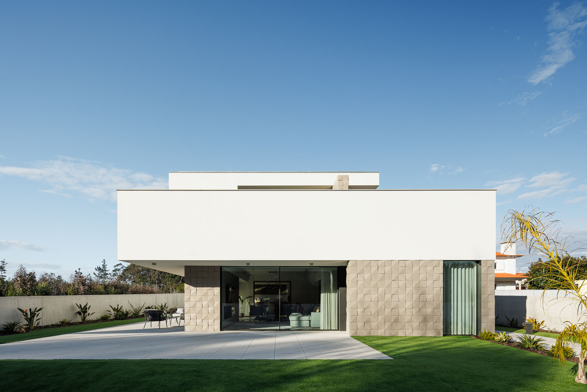Exterior: Fachada moderna com revestimento branco e detalhes em pedra. Jardim relvado. — Casa R.V. arquitetura Atelier d´Arquitectura Lopes da Costa em Ovar