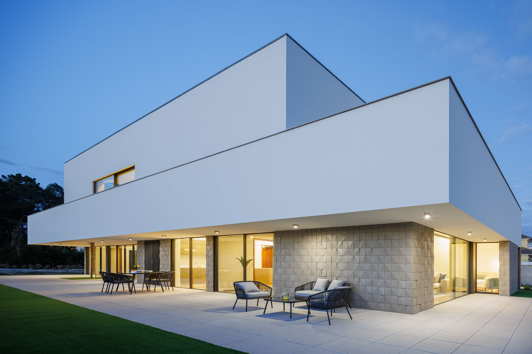 Exterior: Vista da casa ao entardecer, com iluminação exterior e mobiliário de exterior. — Casa R.V. arquitetura Atelier d´Arquitectura Lopes da Costa em Ovar