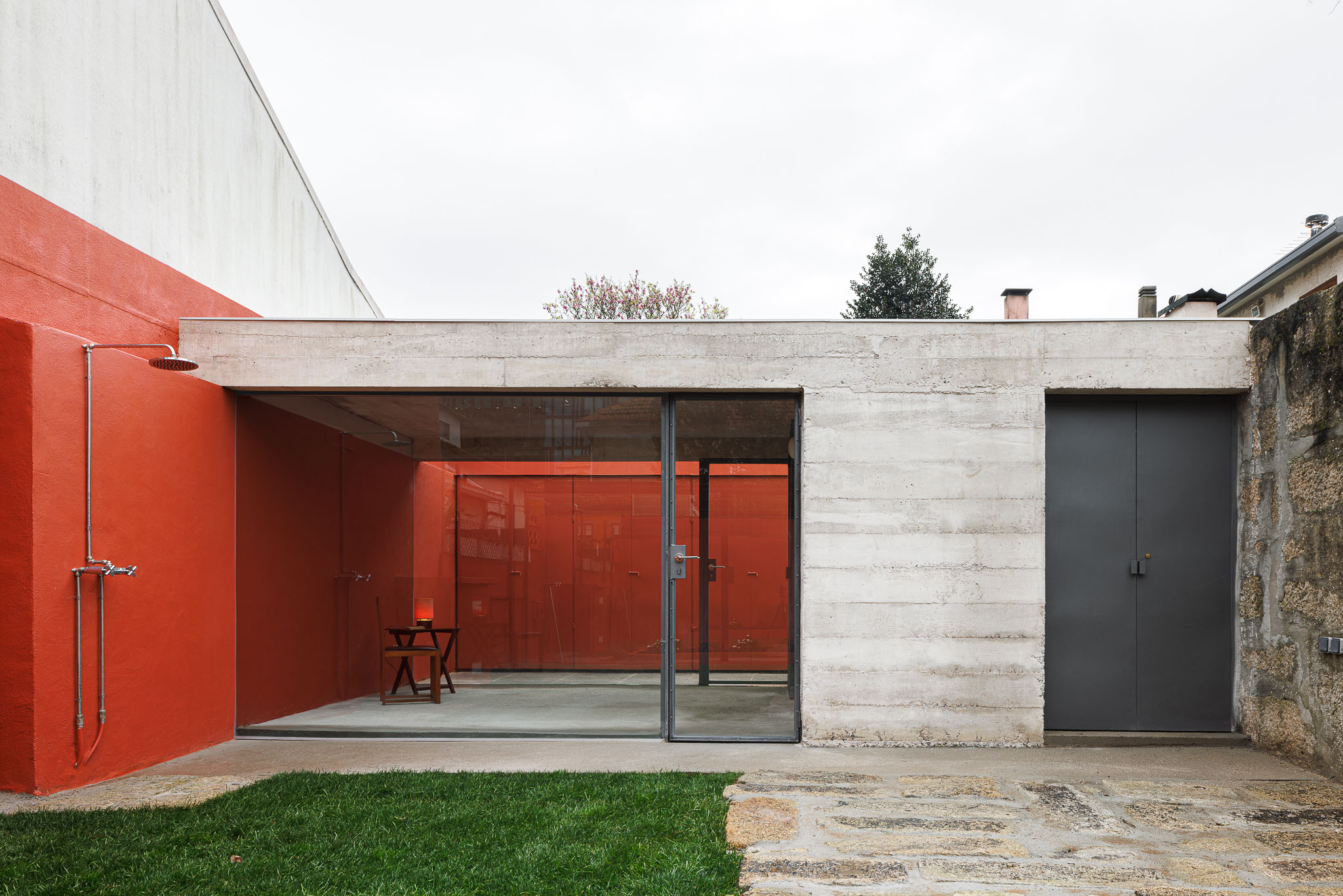 Exterior: Pavilhão com duche, porta de acesso e zona envidraçada, relvado e pavimento em pedra. — Pavilhão de jardim arquitetura José Pedro Lima Arquiteto em Porto