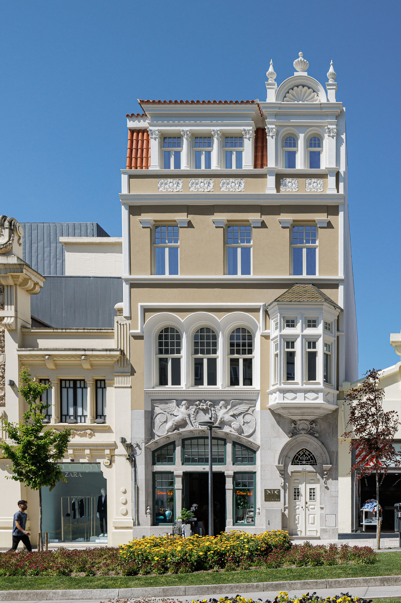 Fachada: Edifício alto com detalhes ornamentais clássicos, janelas em arco e revestimento em tons de bege e branco. — Villa Theatro arquitetura arquitectos aliados em Braga