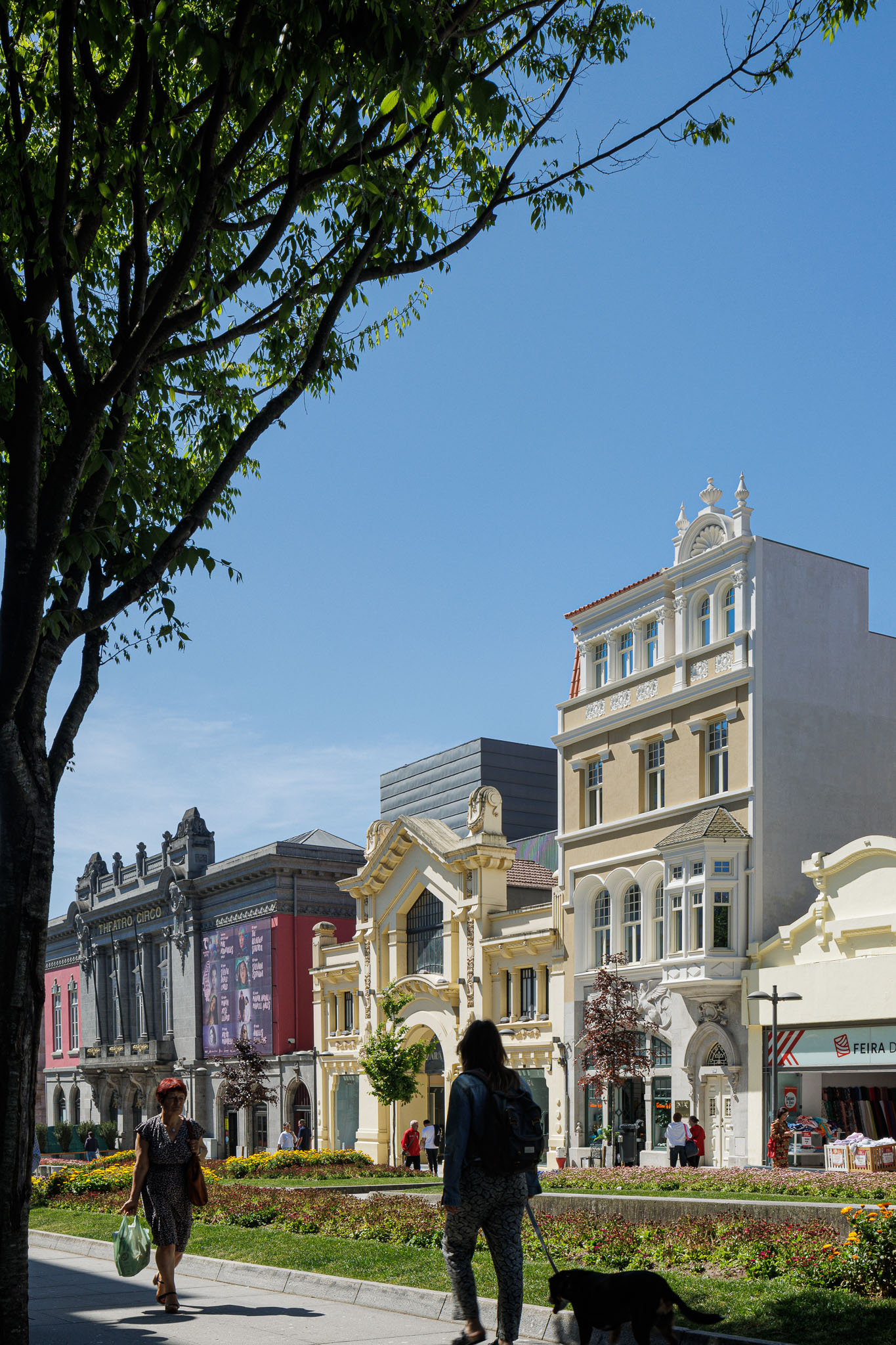 Exterior: Vista da rua com o edifício Villa Theatro integrado na paisagem urbana, com árvores e passeio pedonal. — Villa Theatro arquitetura arquitectos aliados em Braga