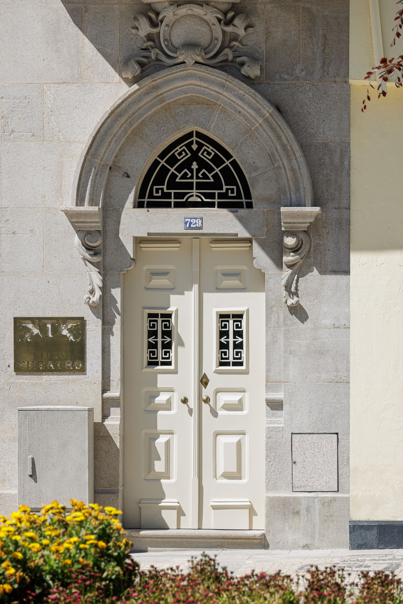 Entrada: Porta de entrada em madeira branca com detalhes em ferro, emoldurada por pedra trabalhada e placa identificativa. — Villa Theatro arquitetura arquitectos aliados em Braga