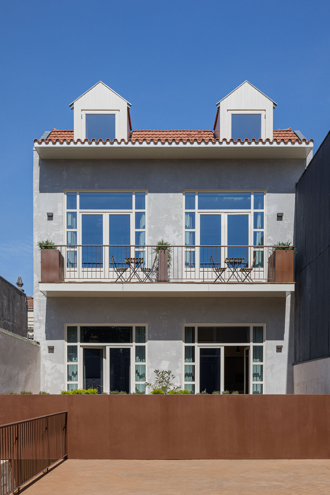 Fachada posterior: Edifício com varandas, janelas amplas e revestimento cinzento, com detalhes em madeira e metal. — Villa Theatro arquitetura arquitectos aliados em Braga