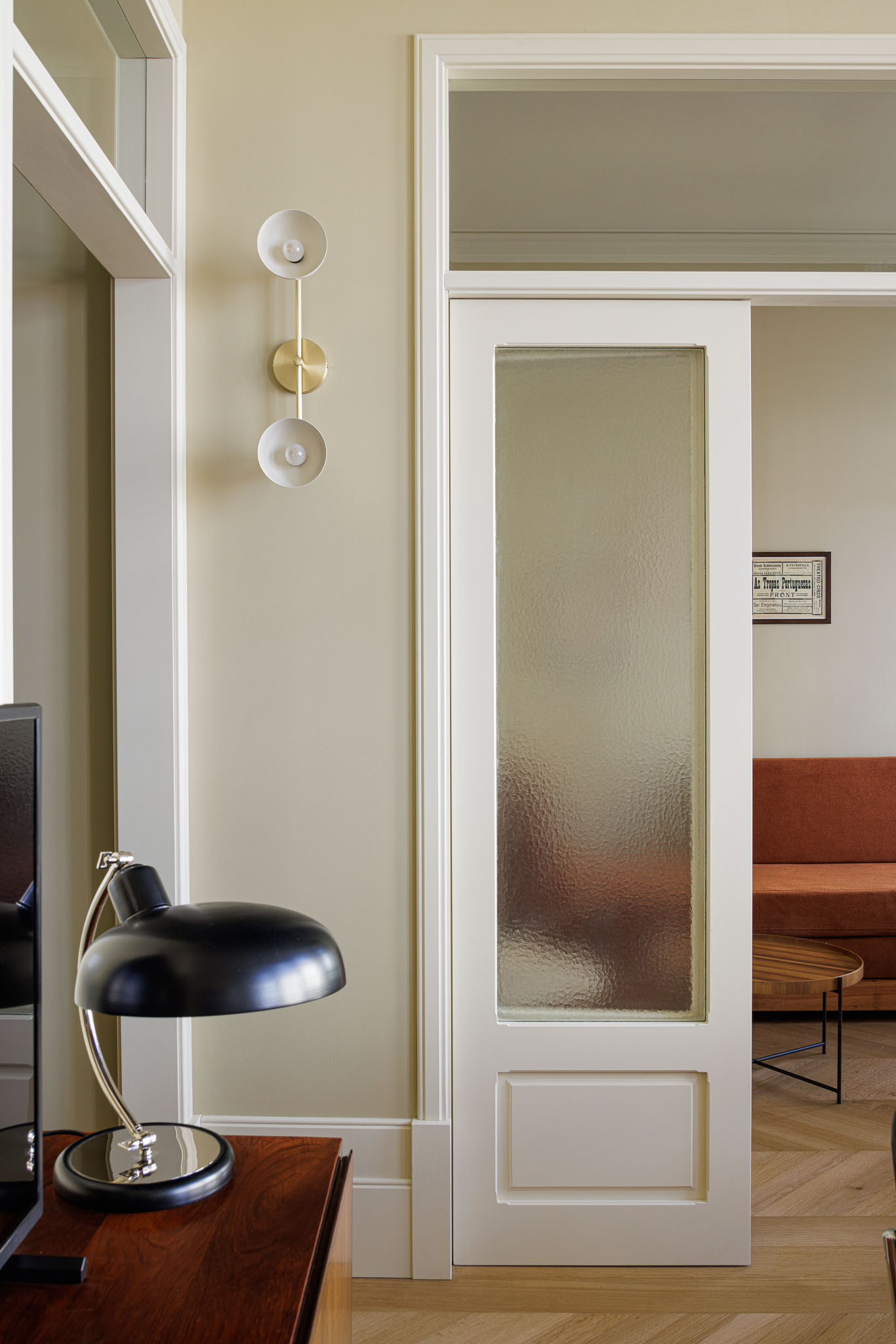 Sala de jantar: Candeeiro de parede com três globos brancos, porta de vidro texturizado e vista para a sala de estar. — Villa Theatro arquitetura arquitectos aliados em Braga