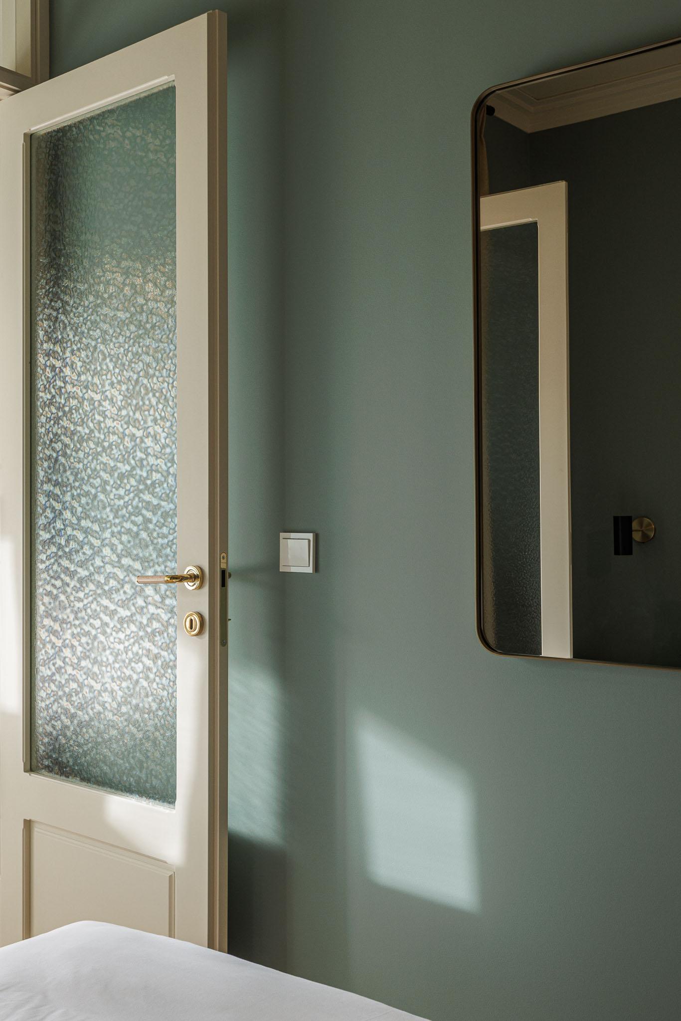 Quarto: Detalhe da porta de vidro texturizado e espelho retangular, com paredes em tons de verde. — Villa Theatro arquitetura arquitectos aliados em Braga
