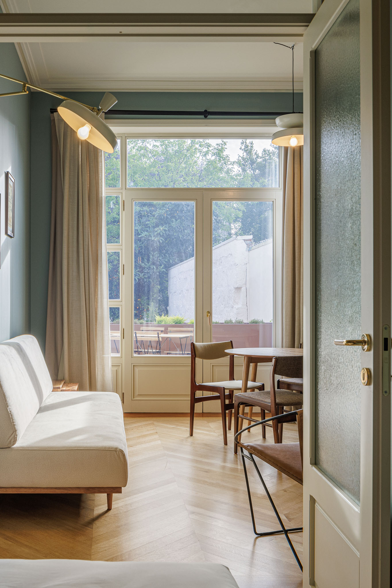 Sala de estar: Sofá branco, mesa redonda e cadeiras em madeira, com pavimento em madeira clara e porta de vidro texturizado. — Villa Theatro arquitetura arquitectos aliados em Braga