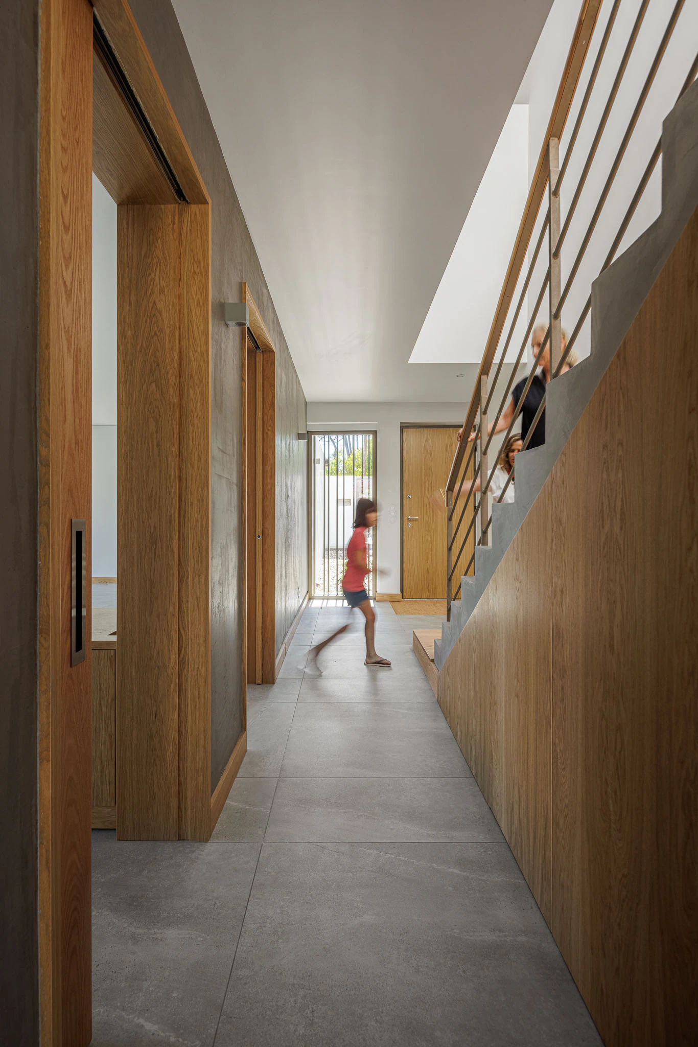 Corredor com portas de madeira, escada e luz natural. Design interior que combina materiais e cores. — Casas do Pinhal arquitetura Pk Arquitetos em Estoril