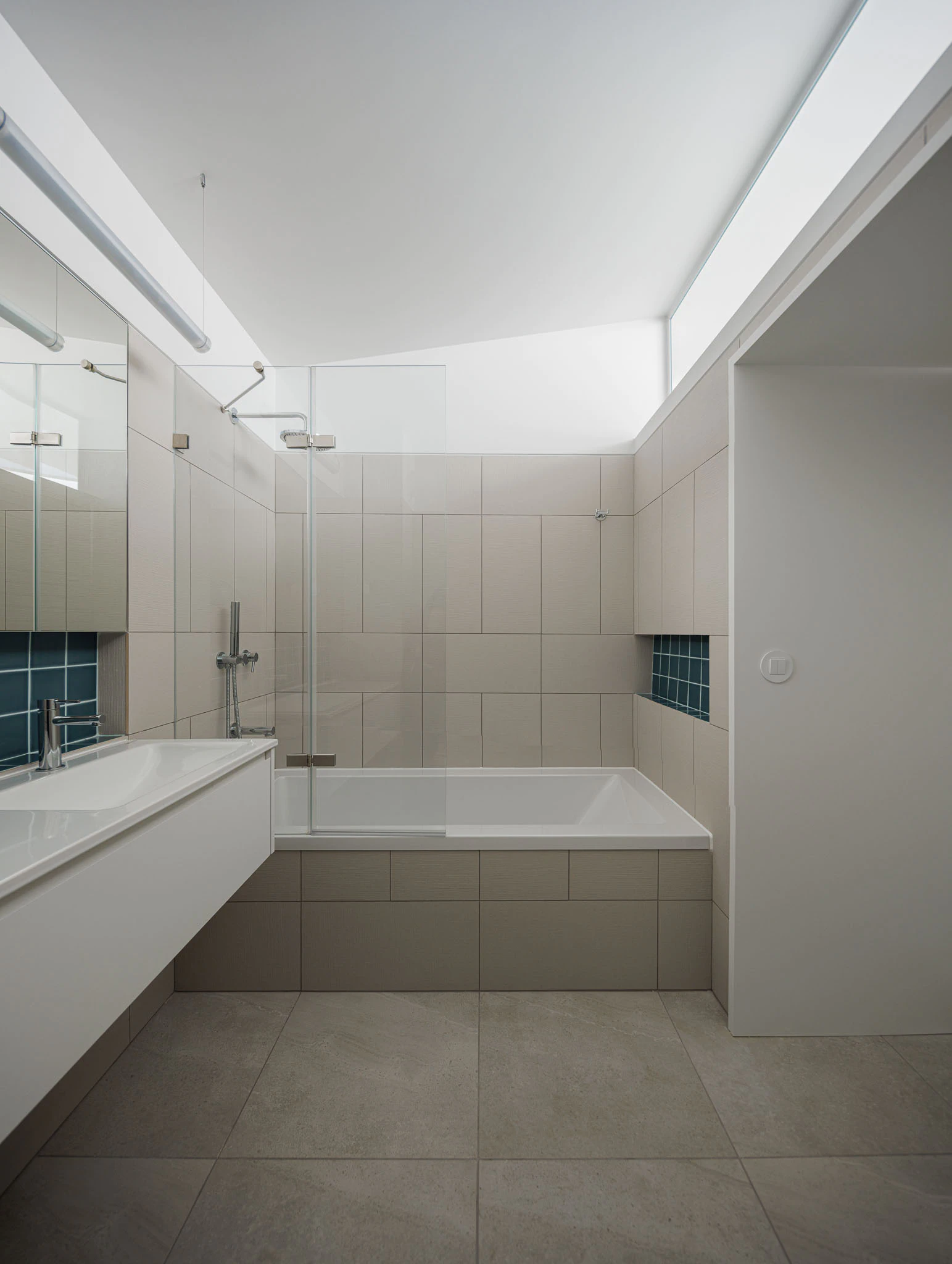 Casa de banho com banheira, lavatório e azulejos cinzentos e azuis. Design moderno e funcional. — Casas do Pinhal arquitetura Pk Arquitetos em Estoril
