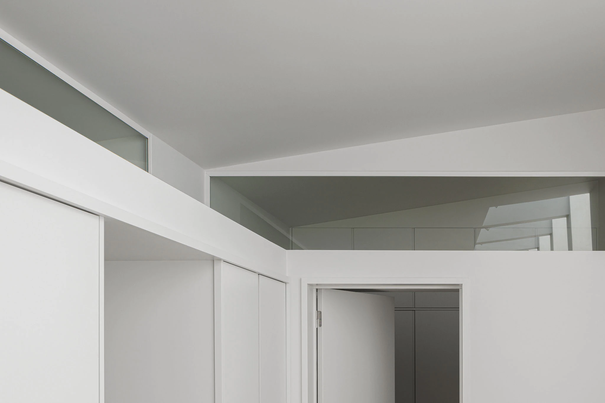 Interior com armários brancos, claraboia e portas. Design minimalista e funcional. — Casas do Pinhal arquitetura Pk Arquitetos em Estoril