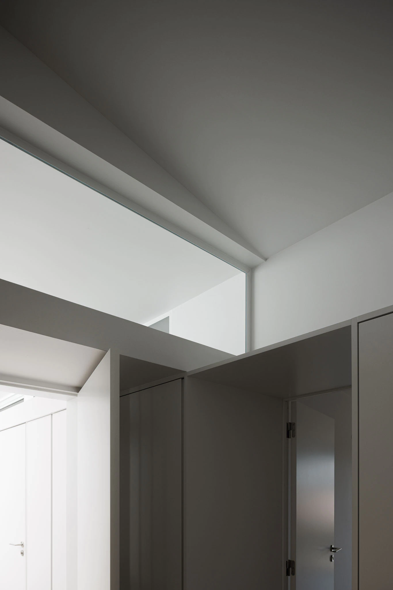Detalhe de claraboia, armários brancos e portas. Design minimalista e funcional. — Casas do Pinhal arquitetura Pk Arquitetos em Estoril