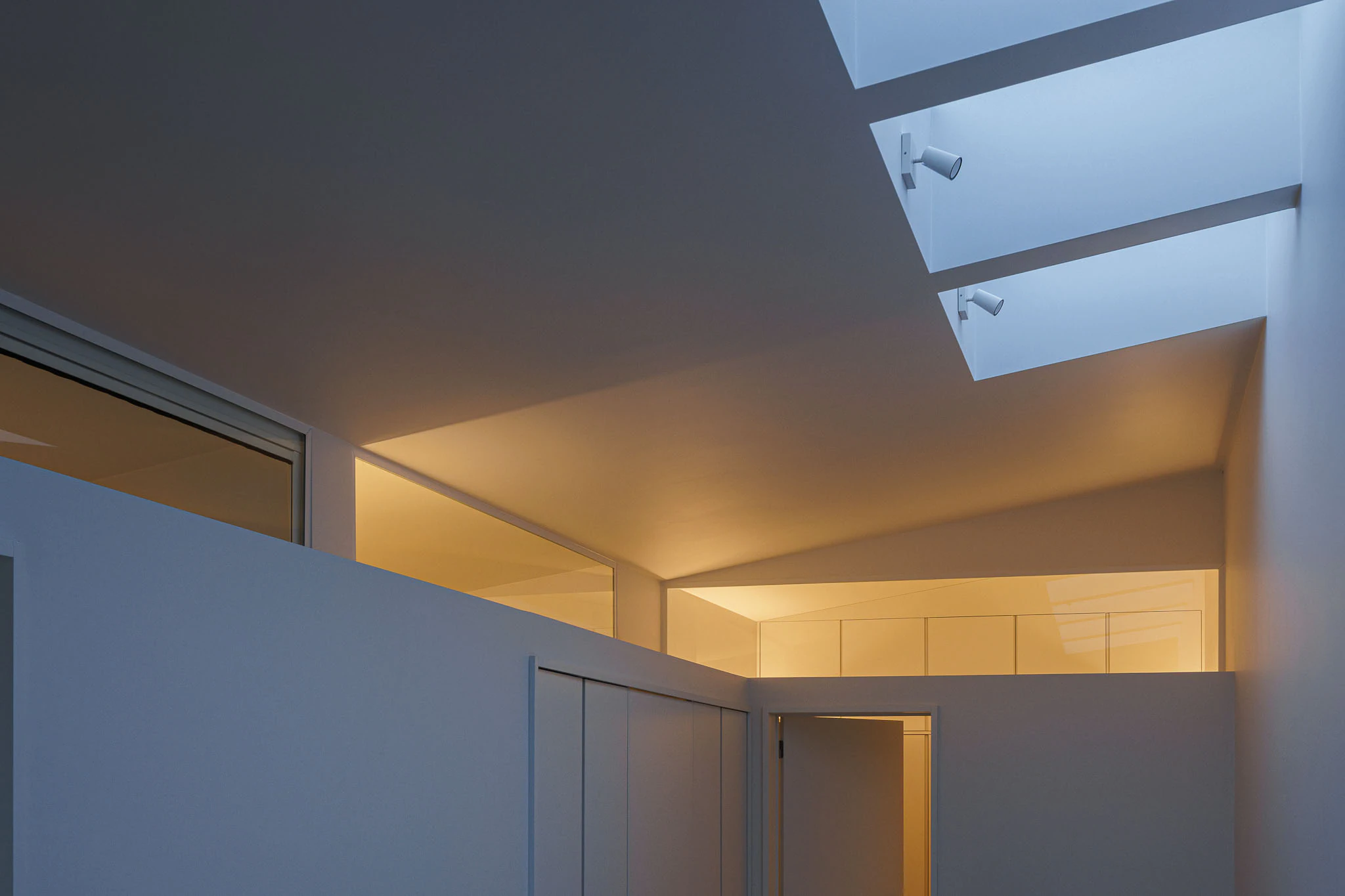 Interior com claraboias, paredes brancas e portas. Design minimalista e luminoso. — Casas do Pinhal arquitetura Pk Arquitetos em Estoril