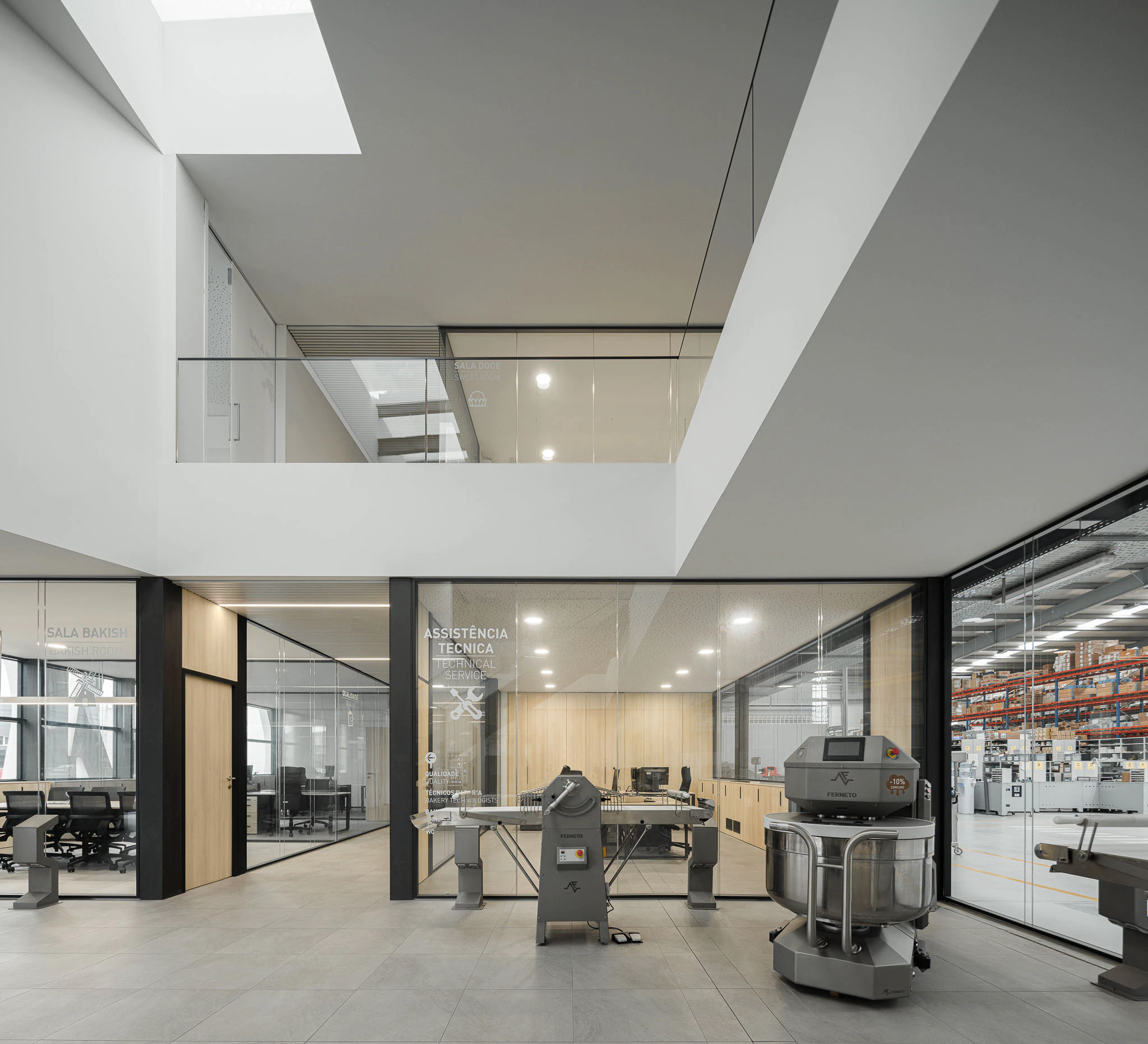 Interior: Espaço amplo com escritórios envidraçados, equipamentos industriais e iluminação zenital. — Ferneto arquitetura Rómulo Neto Arquitectos em Vagos
