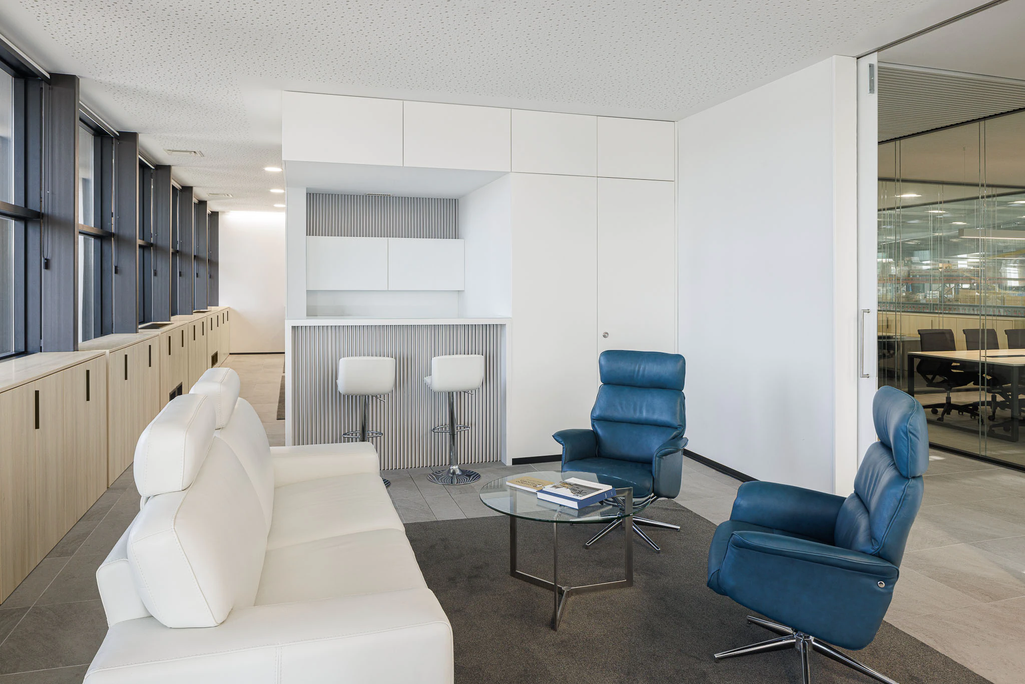 Interior: Zona de estar com sofás brancos, cadeirões azuis e bar minimalista. — Ferneto arquitetura Rómulo Neto Arquitectos em Vagos