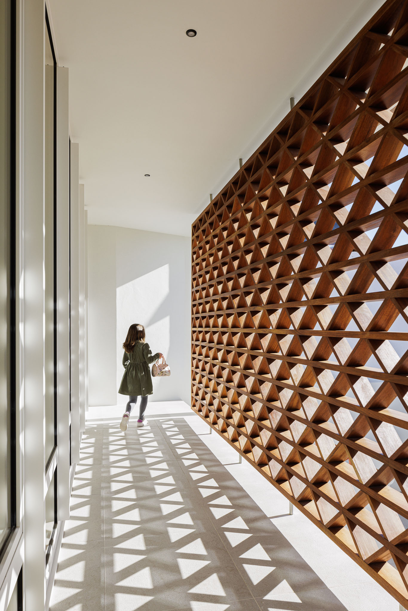 Corredor: Longo corredor com grelha de madeira, pavimento claro e luz natural abundante. — Casa dos anos 40 arquitetura Frari em Ílhavo