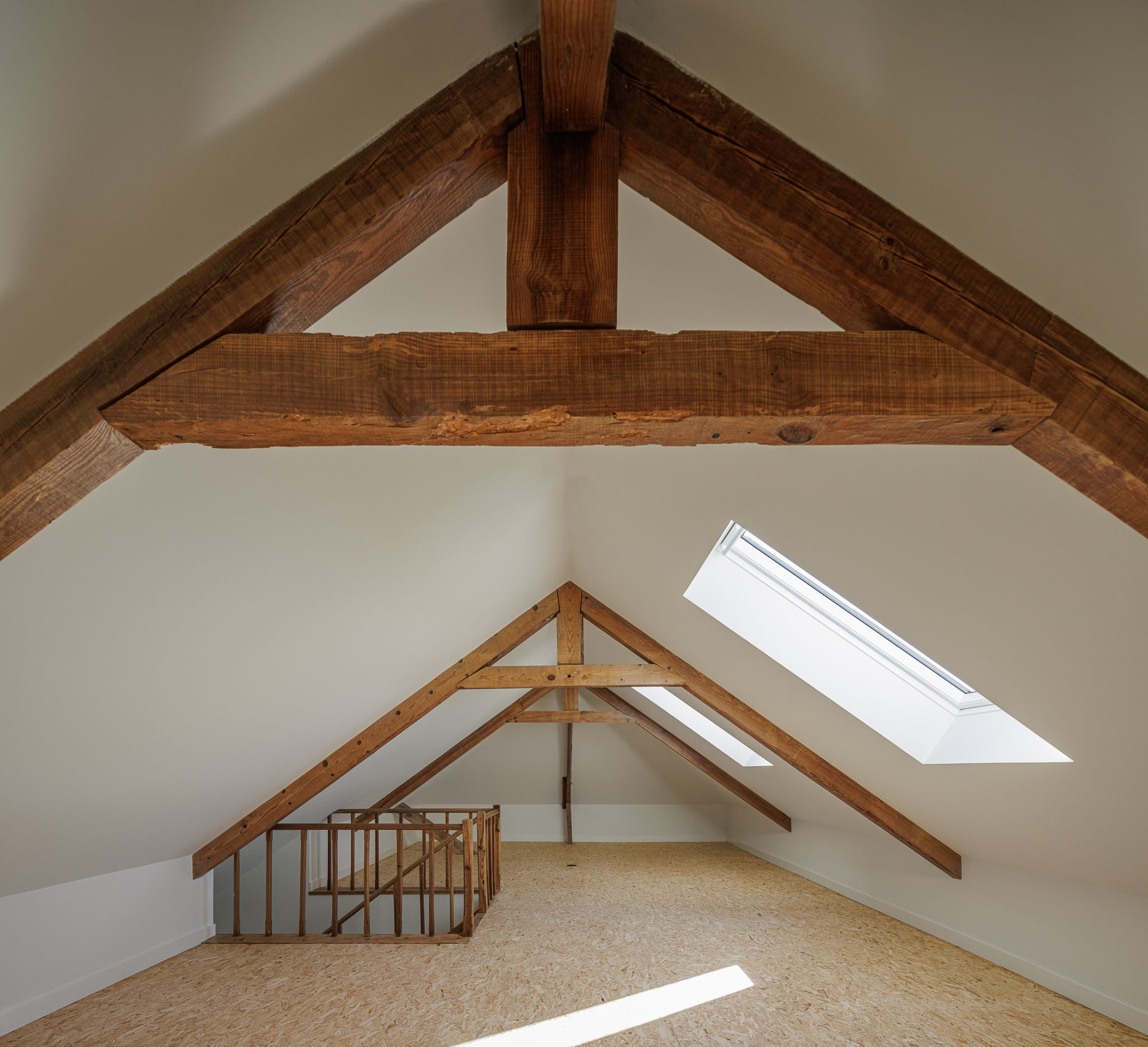 Sótão: Sótão com estrutura de madeira aparente, pavimento em OSB e janela zenital. — Casa dos anos 40 arquitetura Frari em Ílhavo