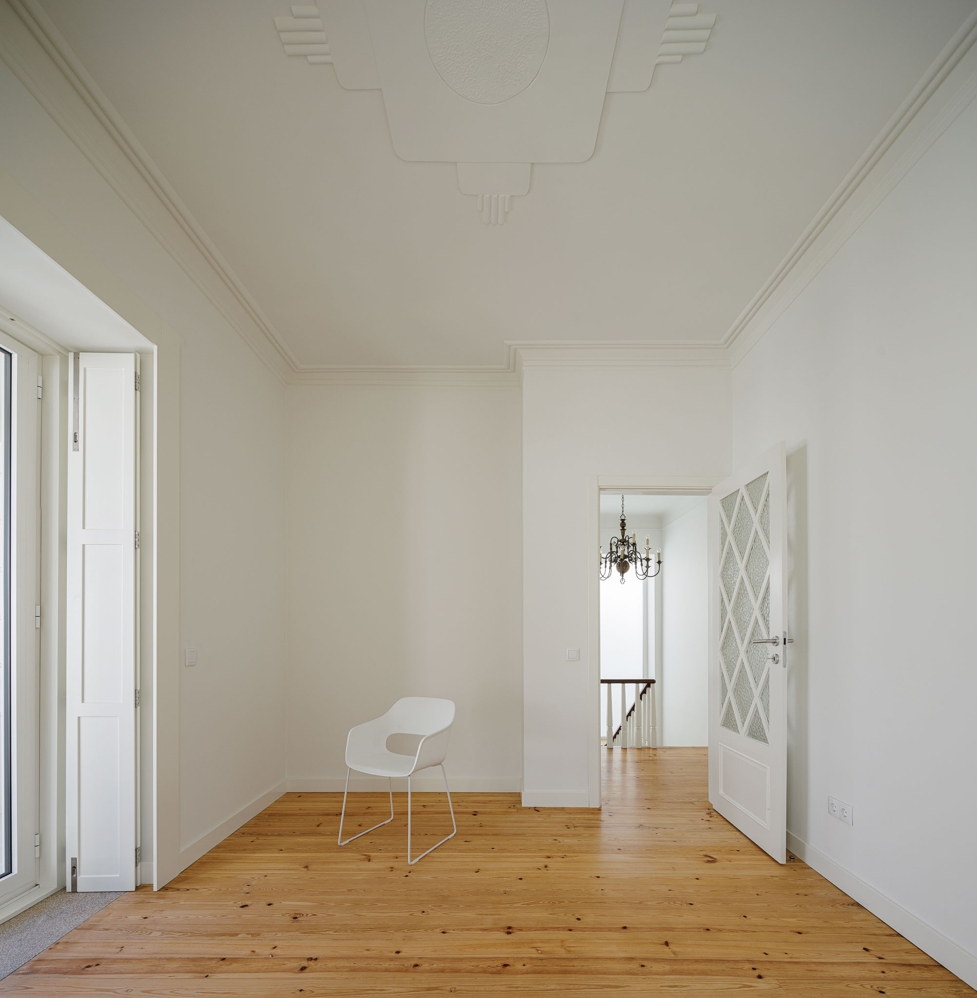 Quarto: Quarto com pavimento em madeira clara, cadeira branca e porta com vidro trabalhado. — Casa dos anos 40 arquitetura Frari em Ílhavo